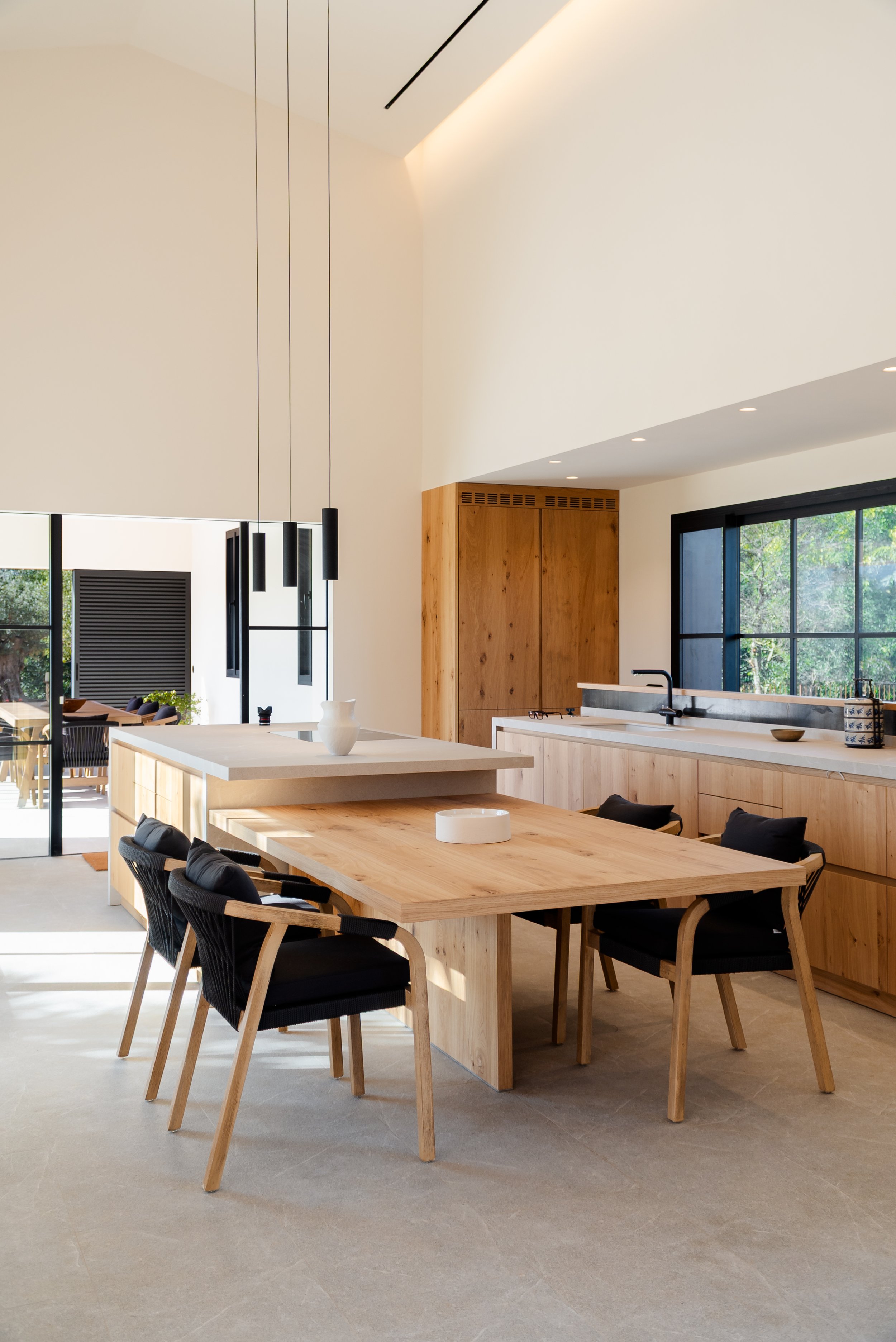 Open-plan kitchen with raw oak island and black pendant lights, architecture by Sebastià Muntaner