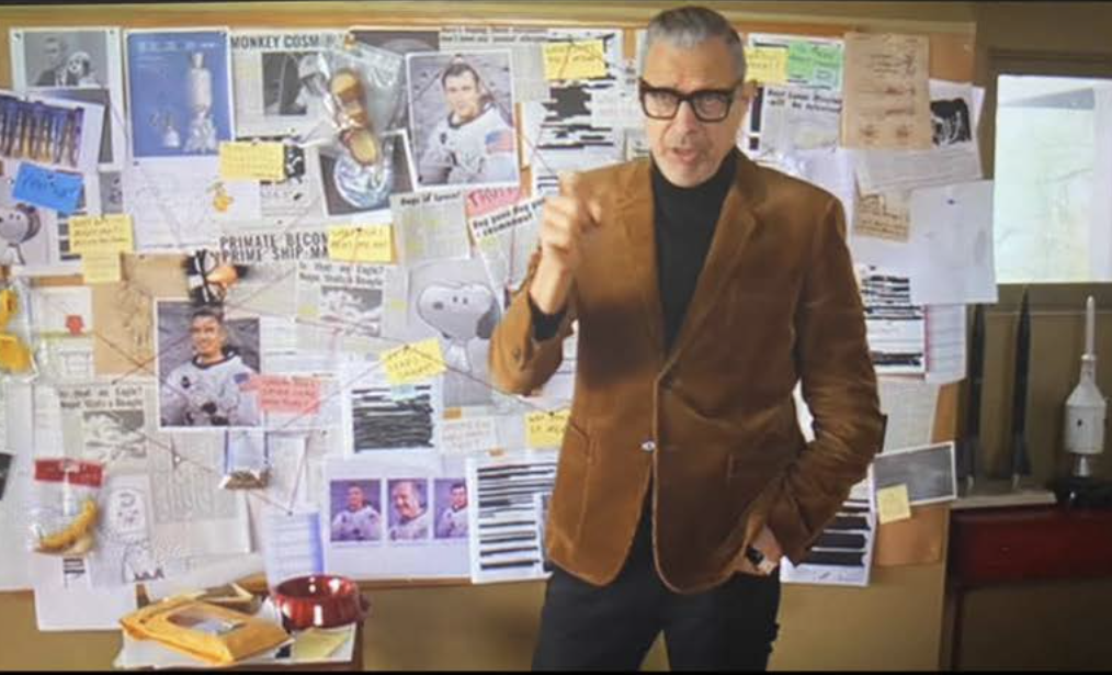 Jeff Goldblum standing in front of a mystery board, props by Lauren Marina.
