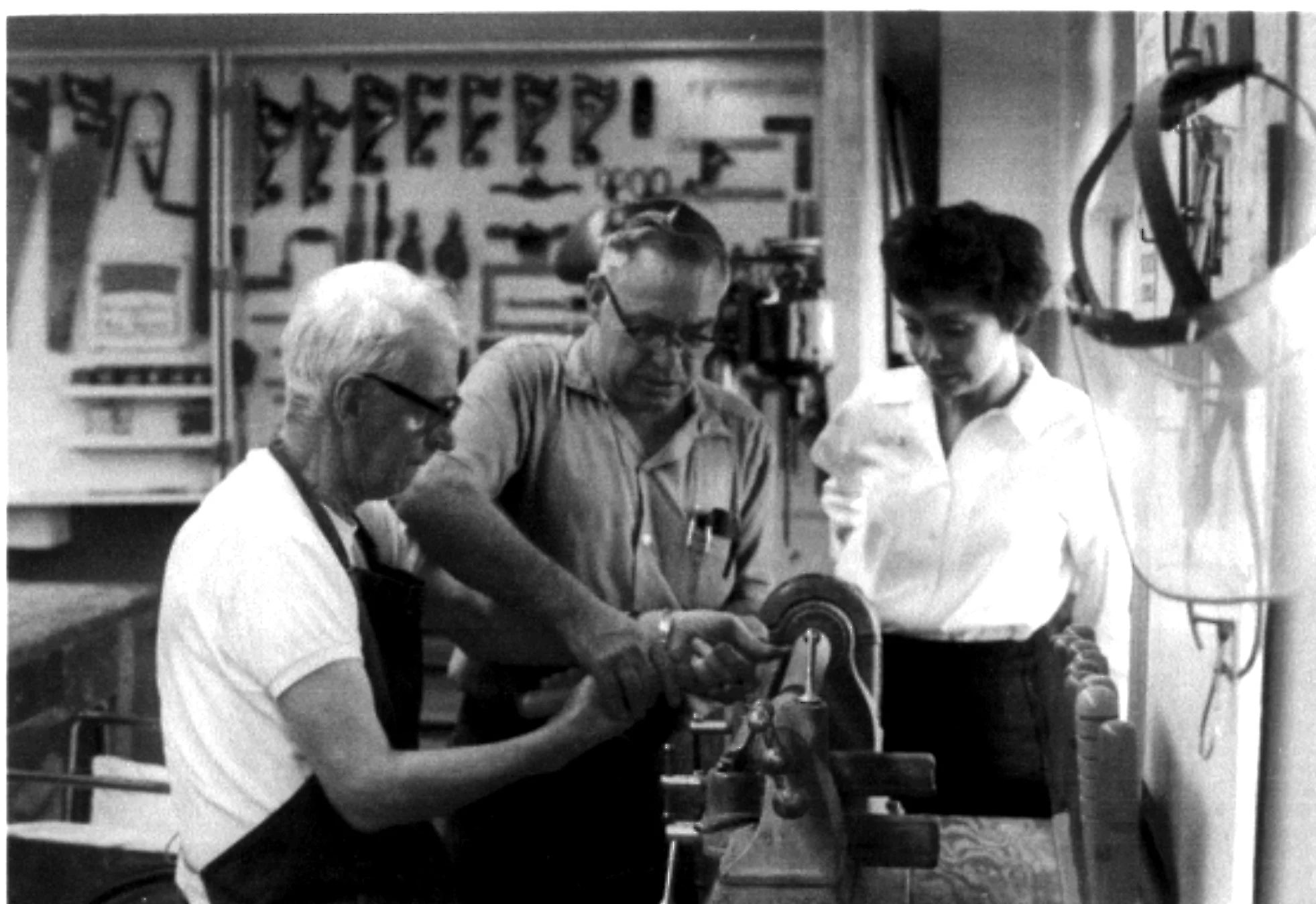An OT guides a client through upper extremity strengthening exercises in a workshop, 1950s. Workshop-based rehabilitation was a hallmark of occupational therapy practice through much of the 20th century.