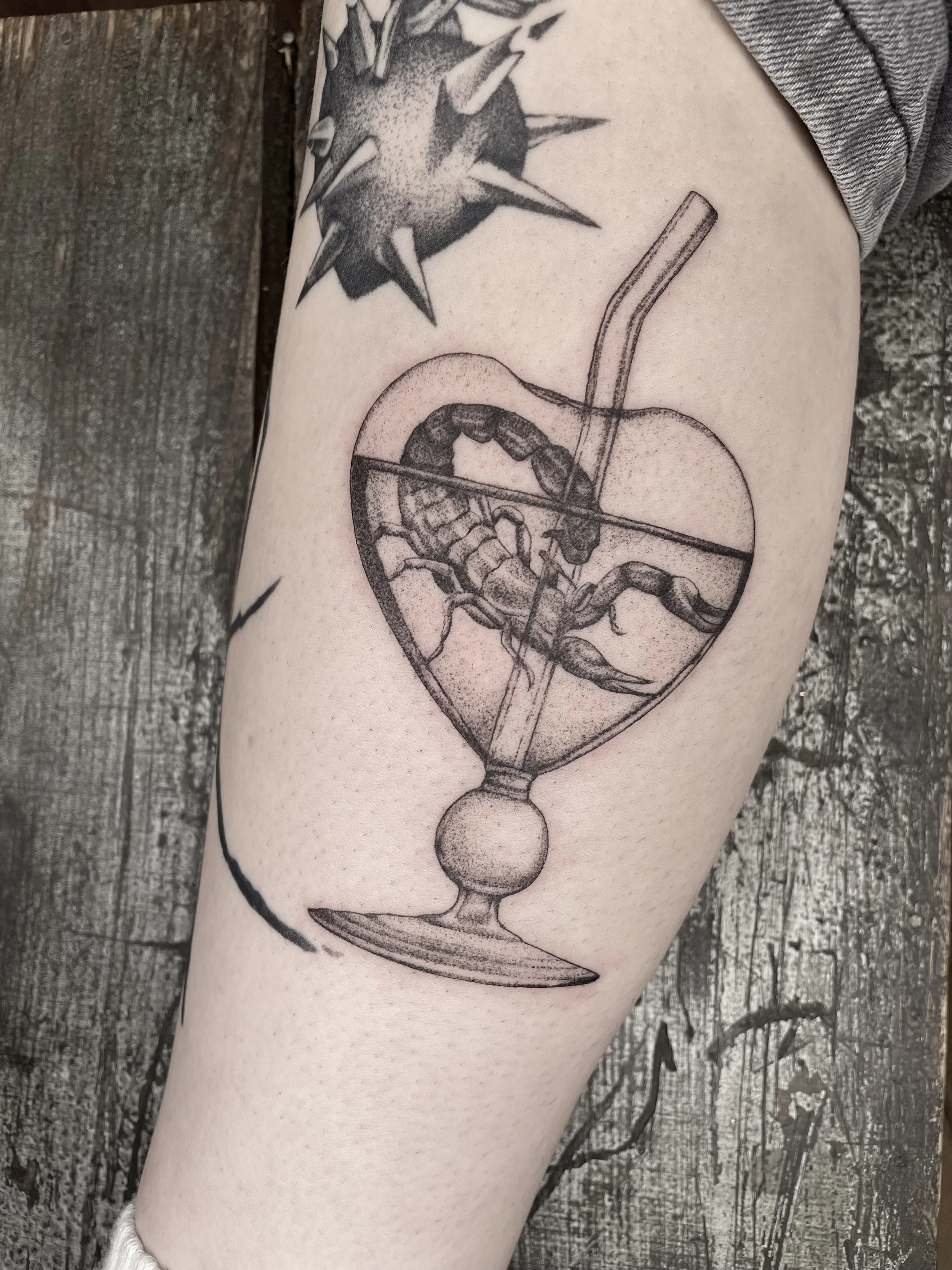 A tattoo on a person's arm of a cocktail glass containing a scorpion