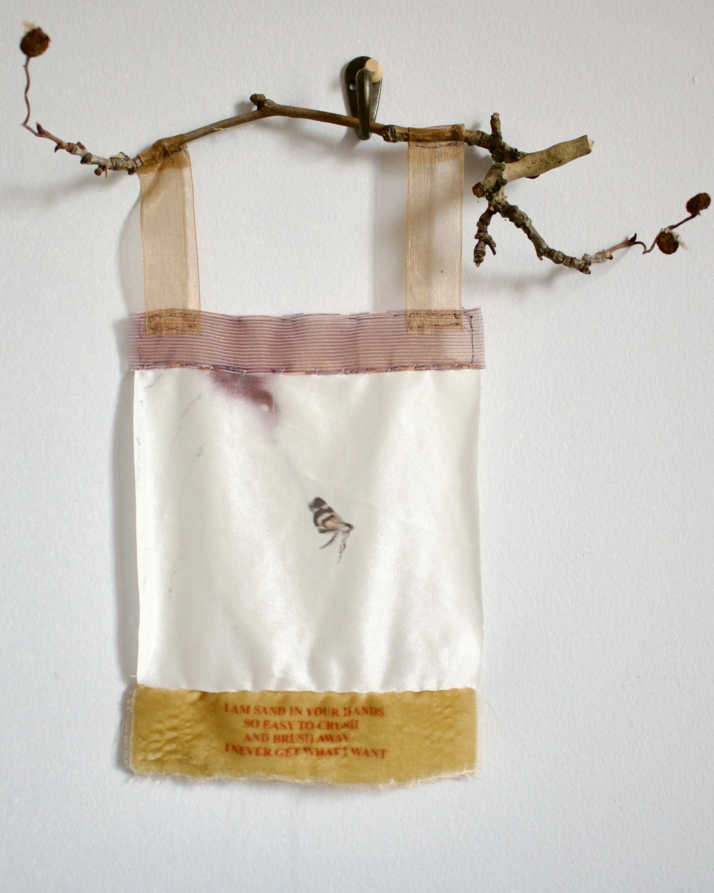 2025. "I am sand in your hands." Inkjet printed found fabric, velvet ribbon, more ribbon, branch. Approx. 12 inches long, 7 inches wide. 