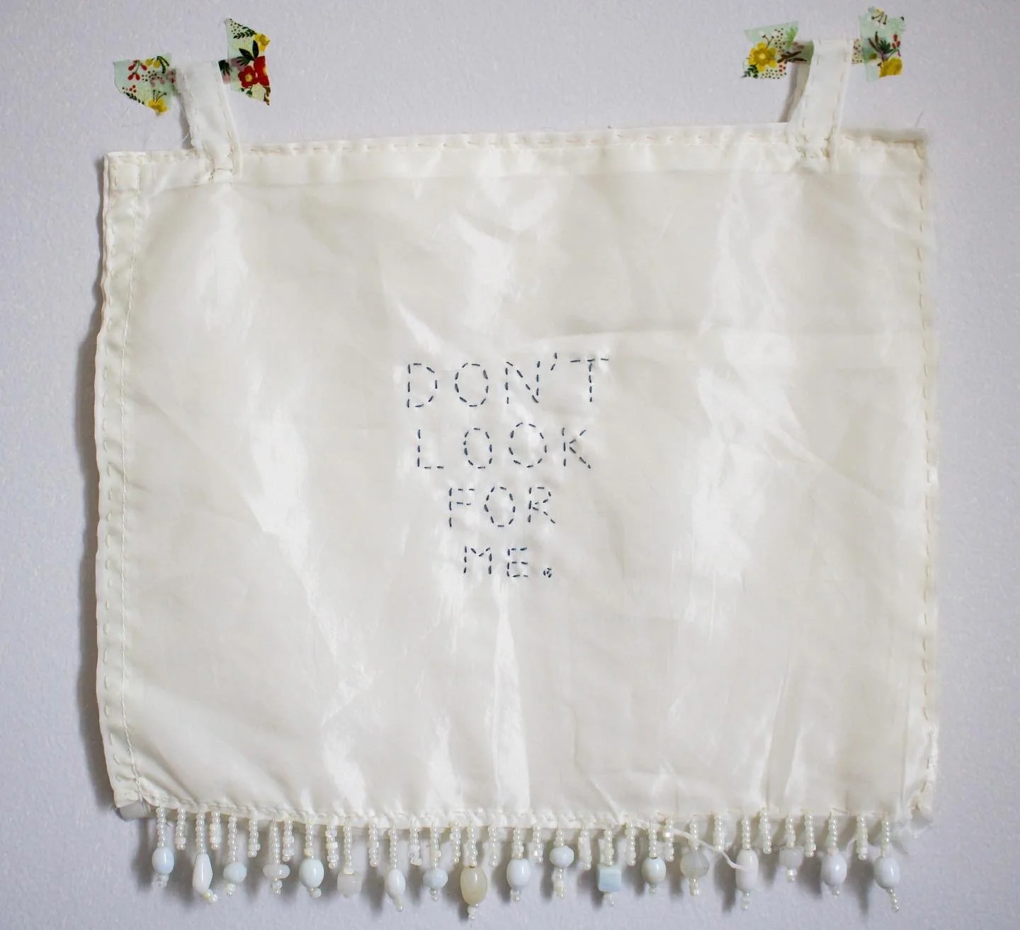 2023. "Don't look for me." 11.5 x 11.5 inches. Satin, thread, and beads (washi tape not included).