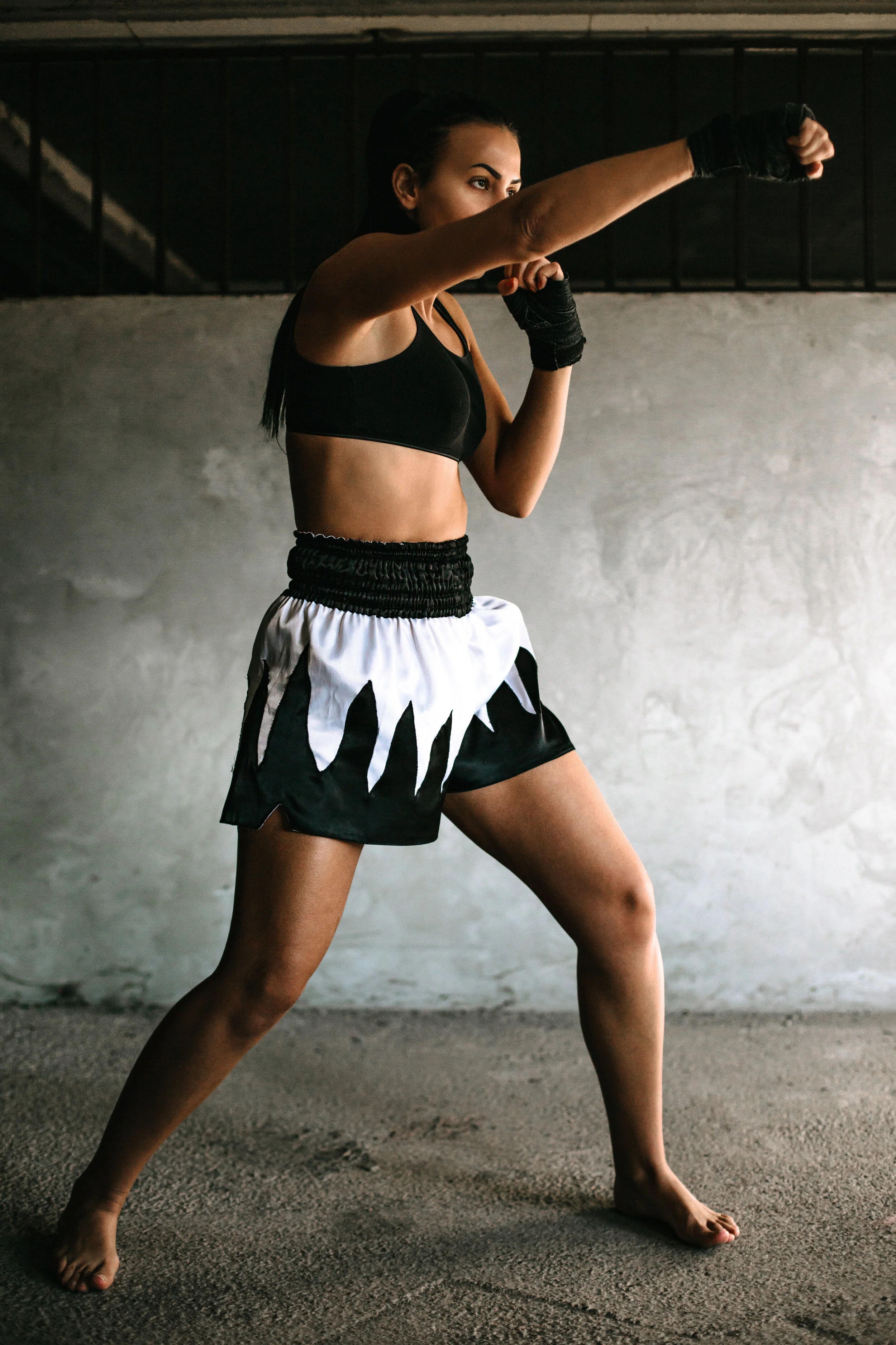 Female martial artist practicing a fighting stance in a gym.