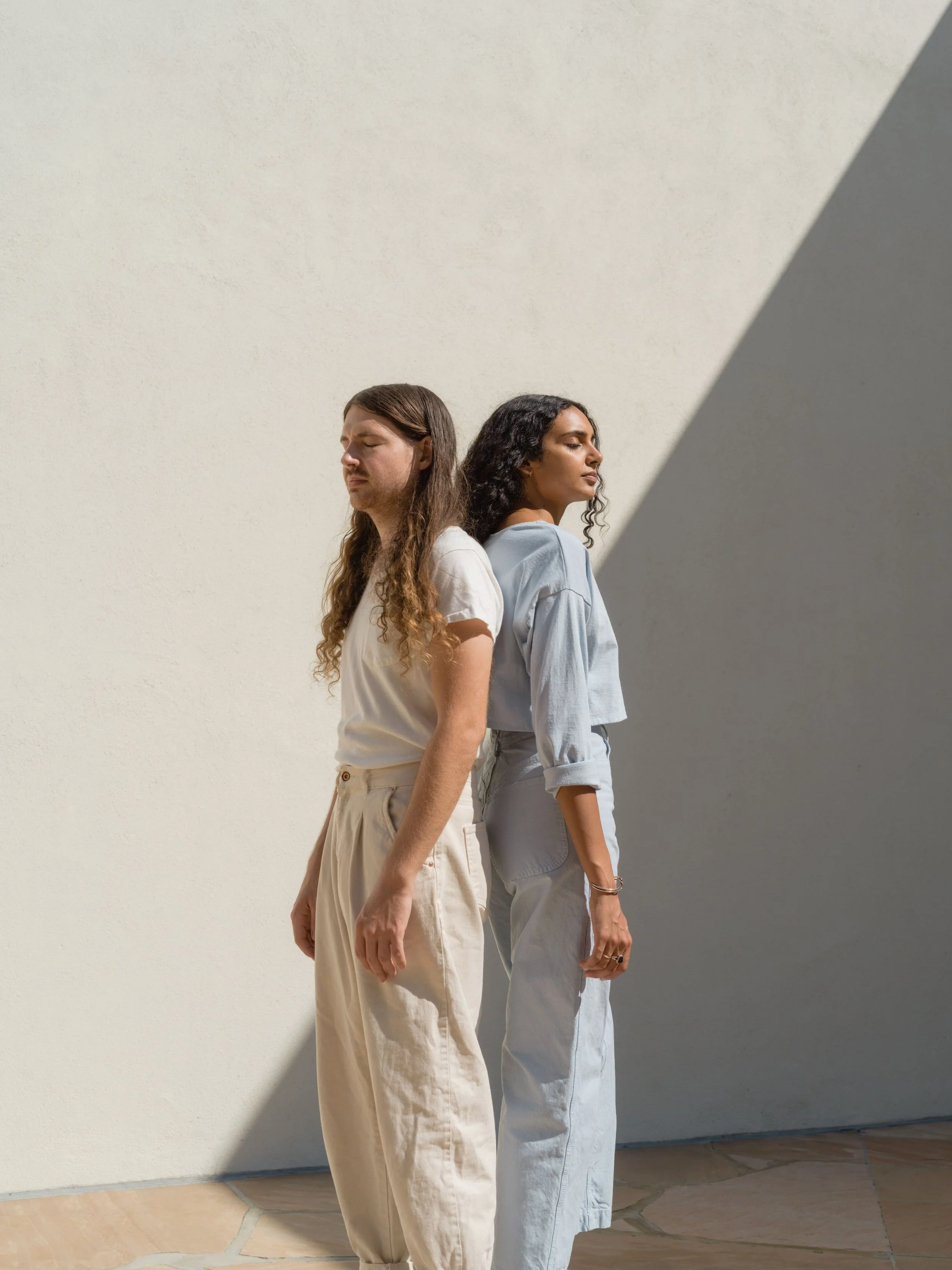 Hombre y mujer a la moda de pie con sombra