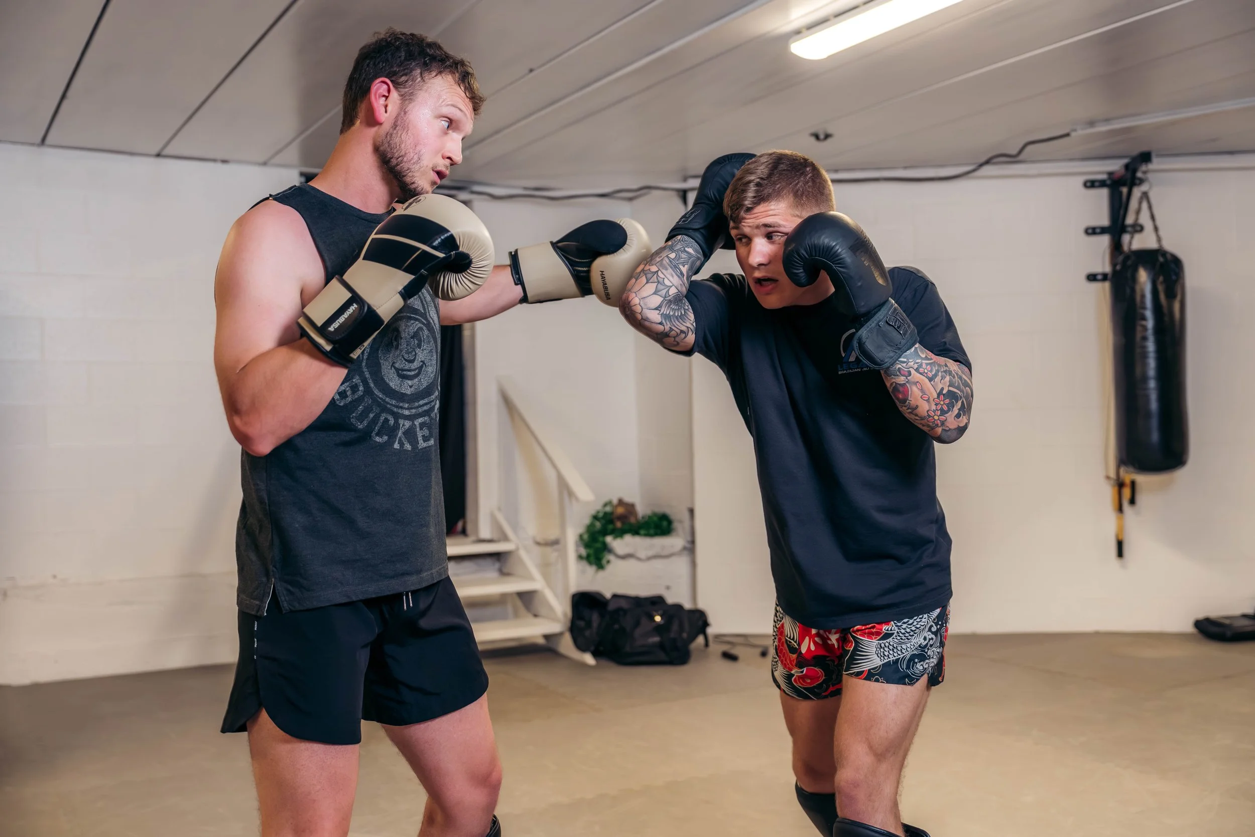 Two men boxing in a gym, one throwing a punch while the other blocks.