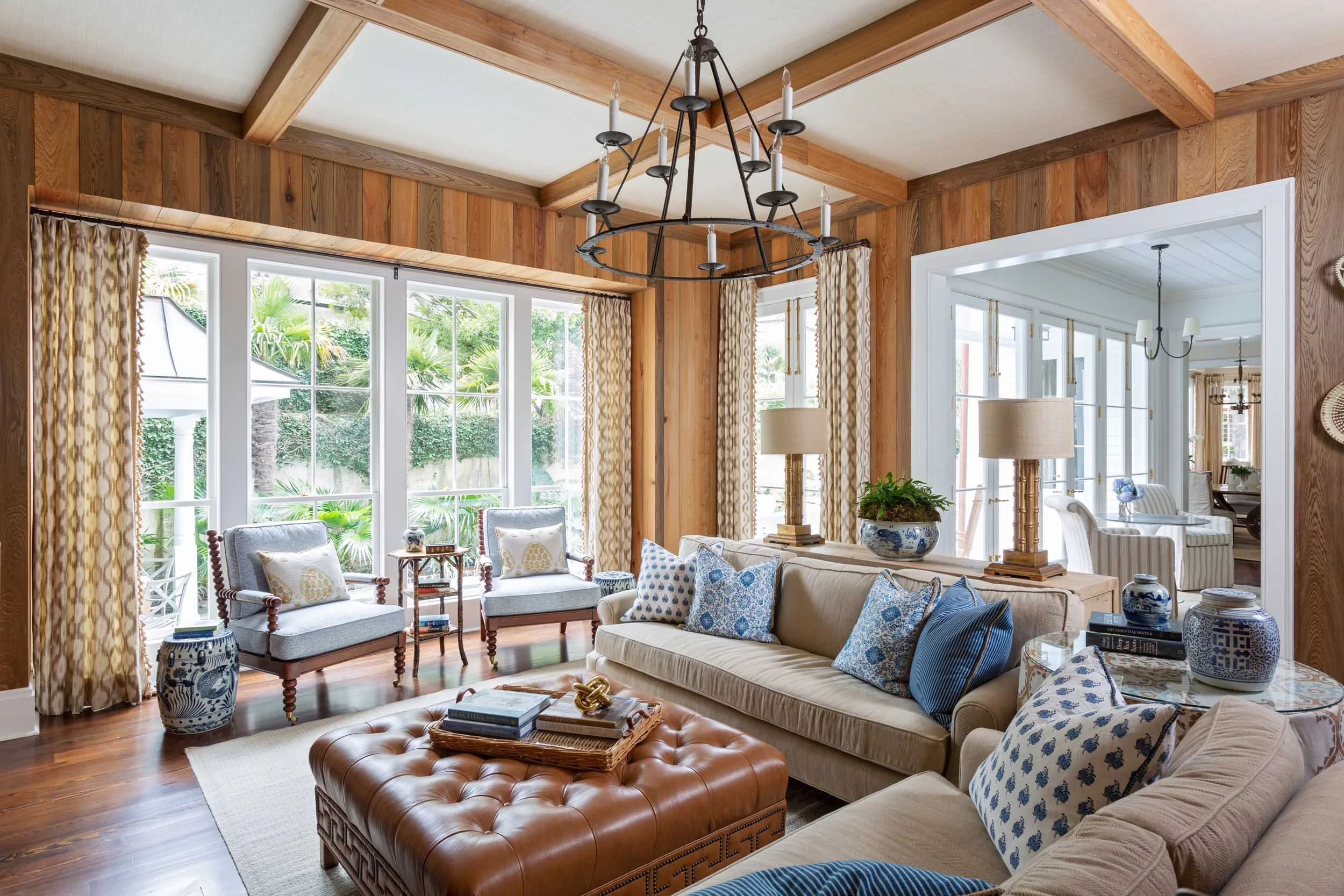 family-room-featuring-pecky-cypress-walls-and-chenille-covered-sofas-and-tufted-leather-ottoman.jpg