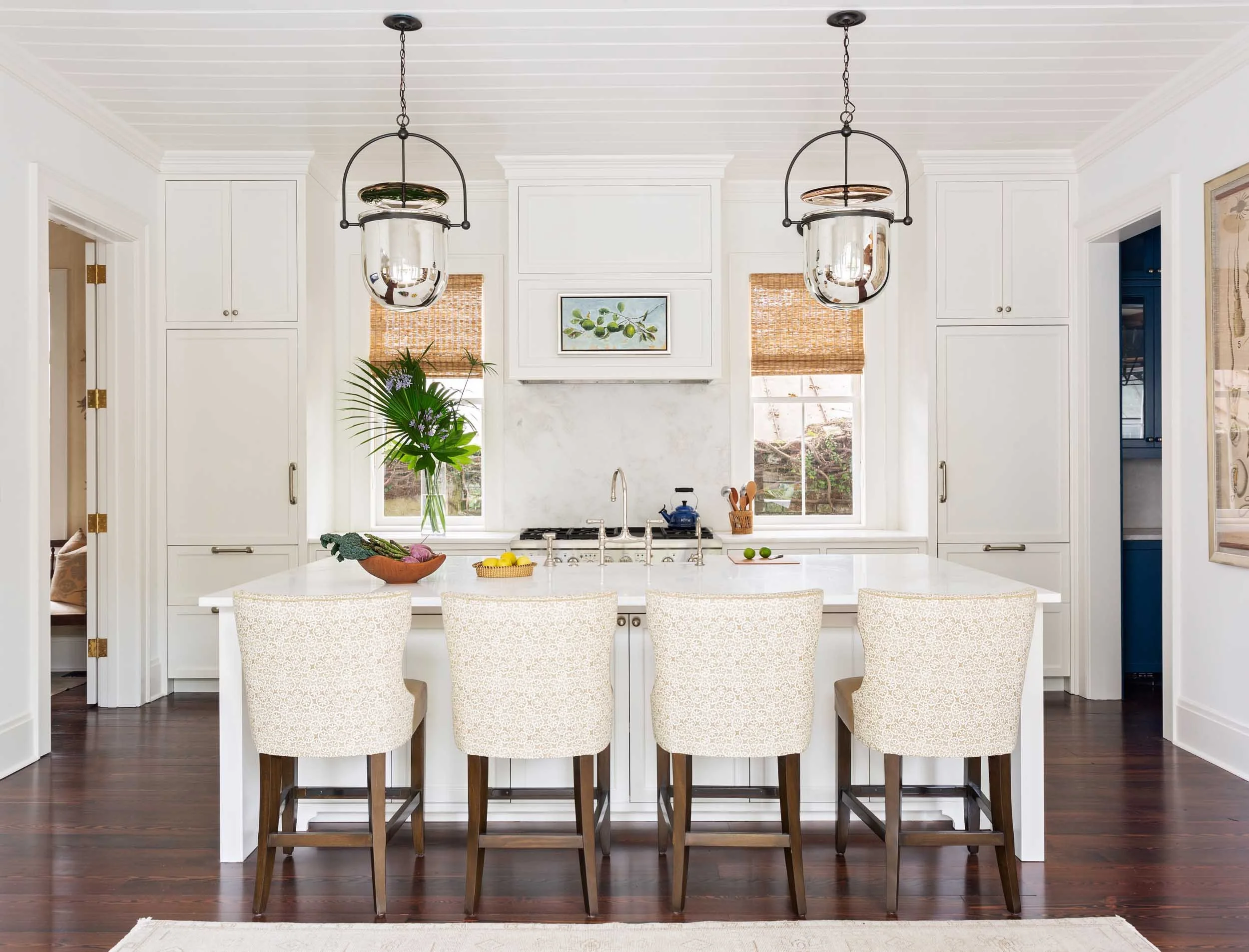 bright-and-open-kitchen-island-with-custom-linen-and-leather-barstools-lit-by-chrome-bell-jar-urban-electric-pendants.jpg