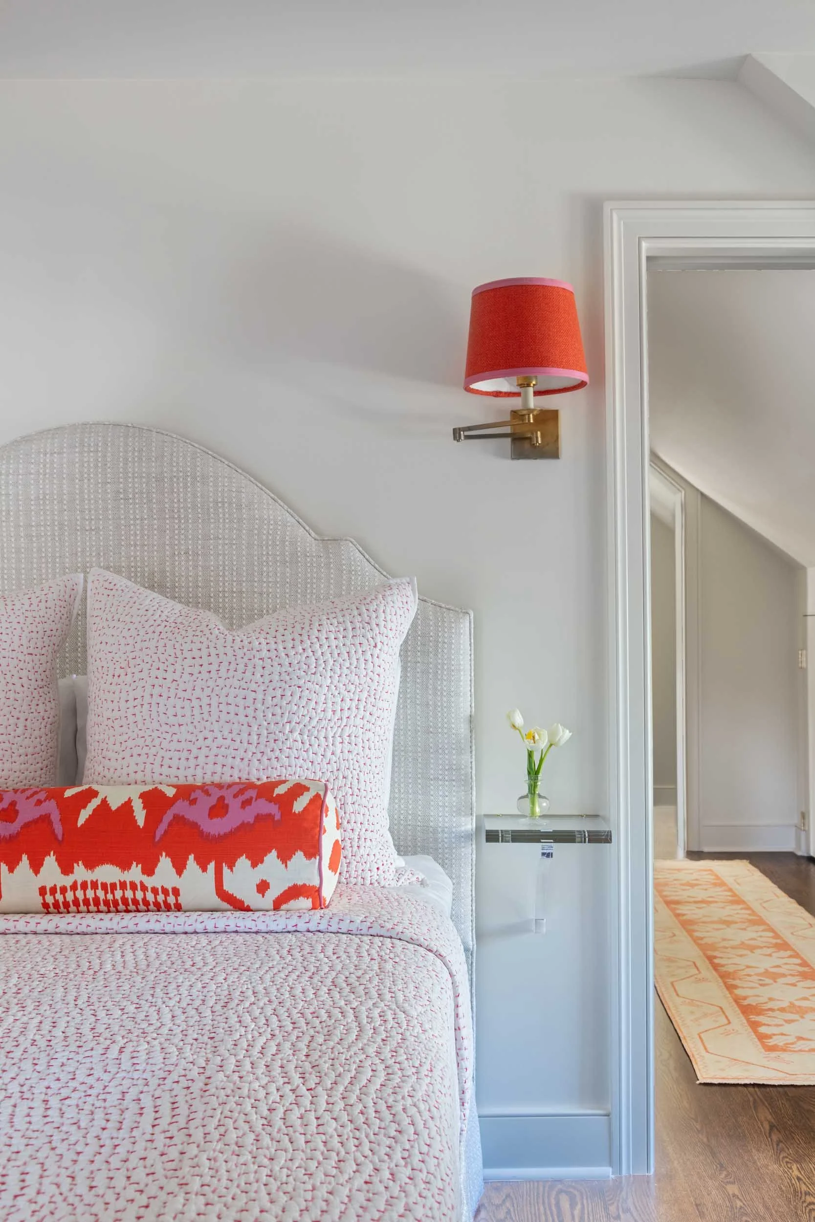 third-floor-bedroom-custom-headboard-brass-sconce-orange-linen-pink-trim-john-rodshaw-bedding-custom-space-saving-acrylic-side-table.jpg