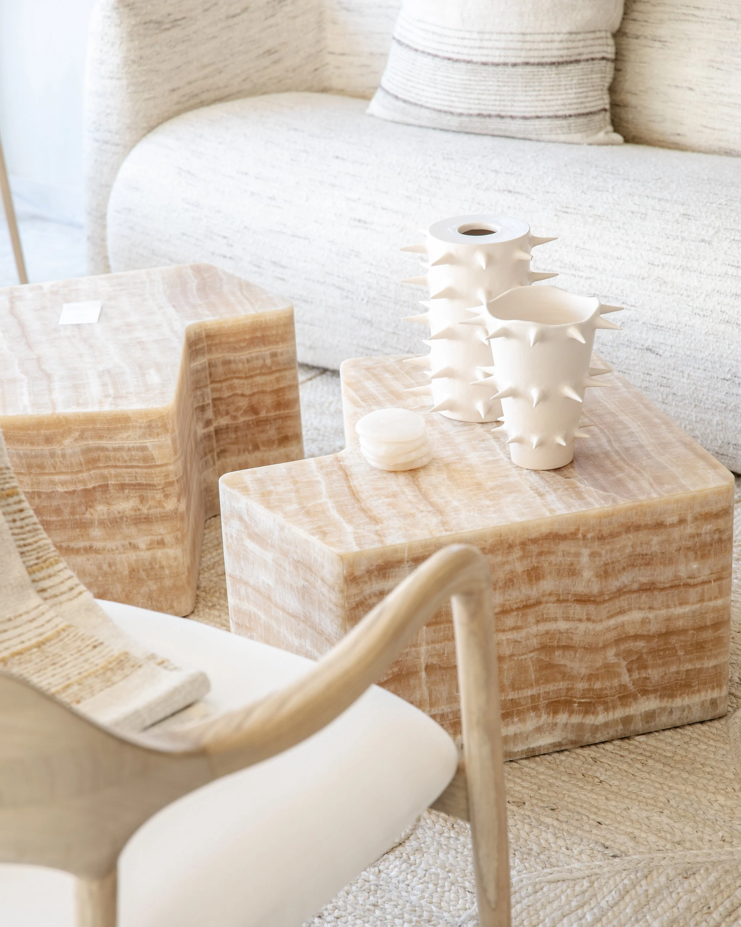 Living room with beige sofa, wooden side tables, and decorative ceramic vases with spikes.