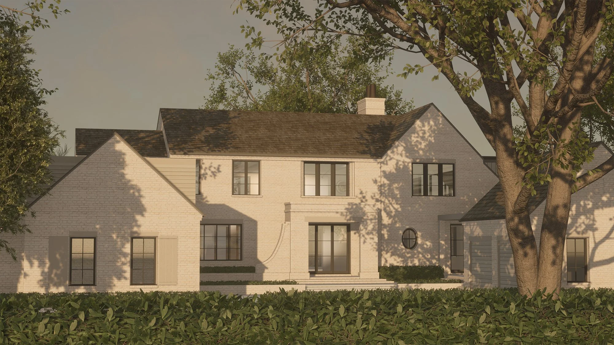 A two-story house with a white brick exterior, multiple black-framed windows, a small front porch with steps, and a large tree in the front yard with sunlight casting shadows on the house.