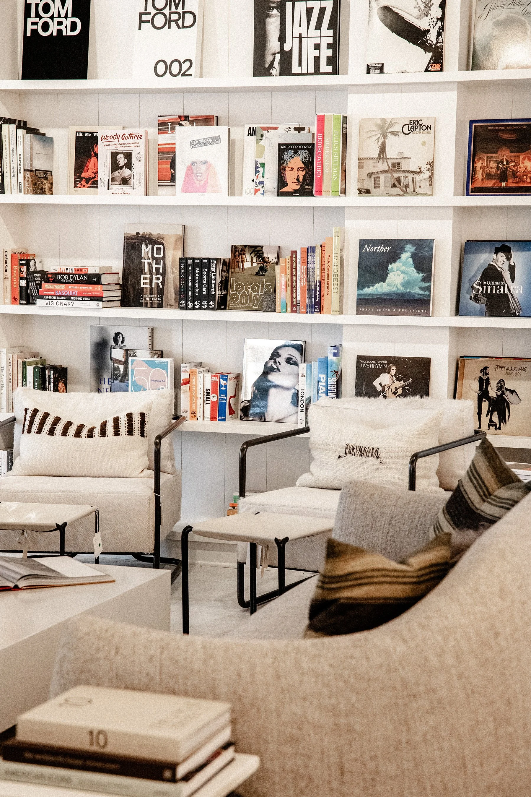 A cozy reading corner with bookshelves filled with music and art books, and comfortable chairs with pillows.