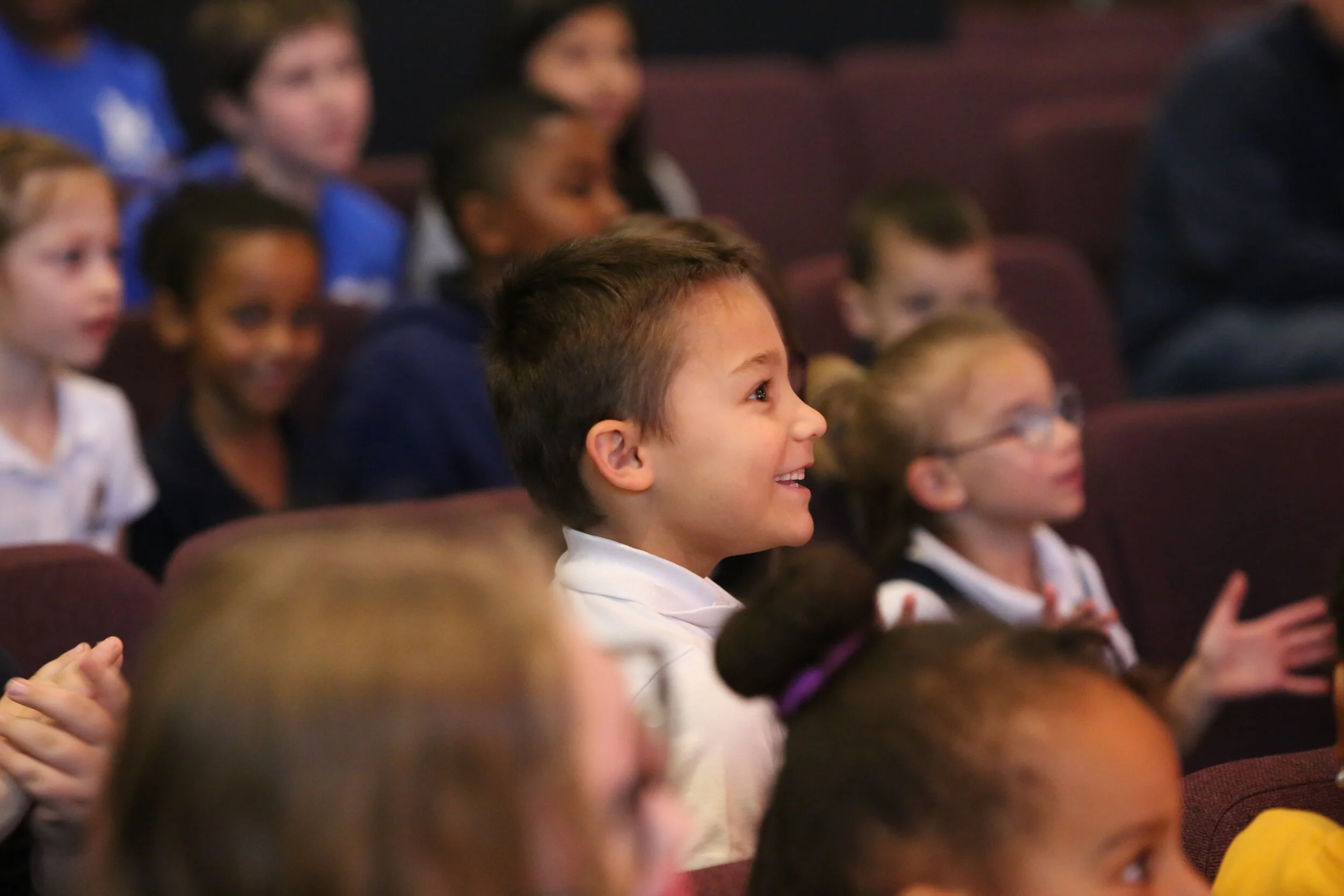 young elementary-aged boy smiling during chapel at Community of Grace Christian School in White Bear Lake, MN
