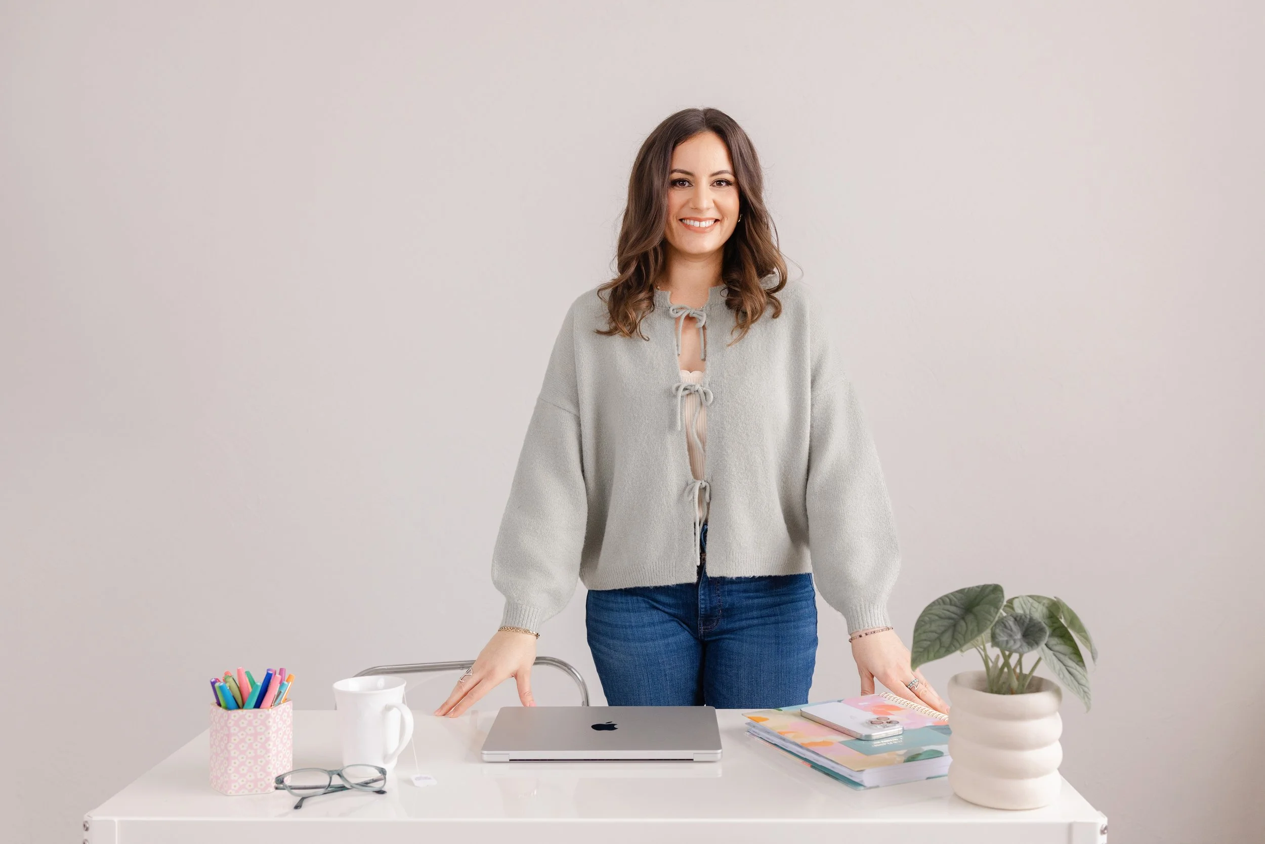 Woman standing at office desk smiling.