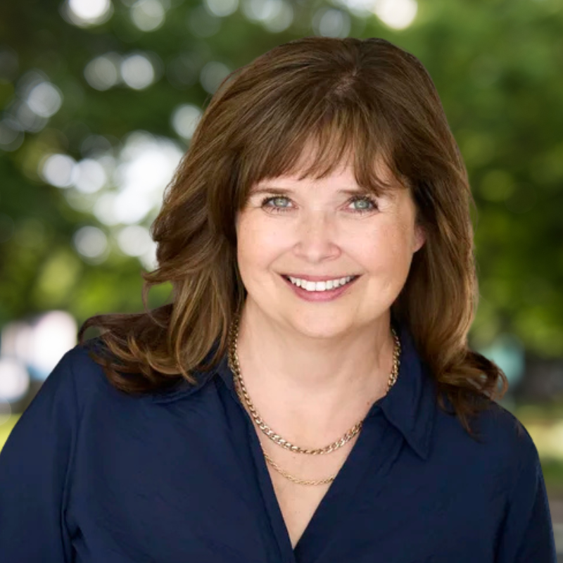 Woman with short brown hair, smiling and wearing a dark navy shift.