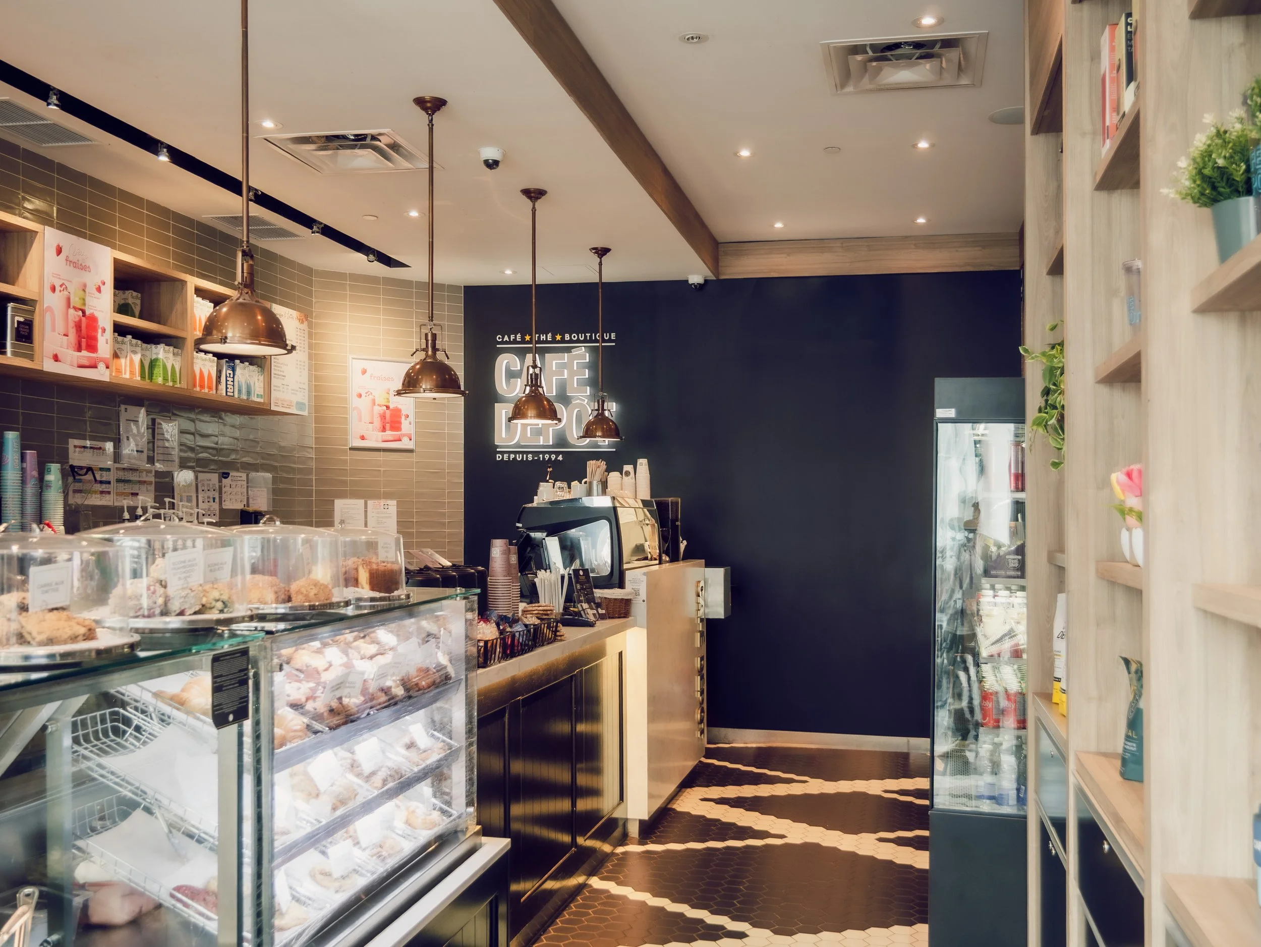 Interior of a modern coffee shop with display case of pastries, shelves of products, and seating area