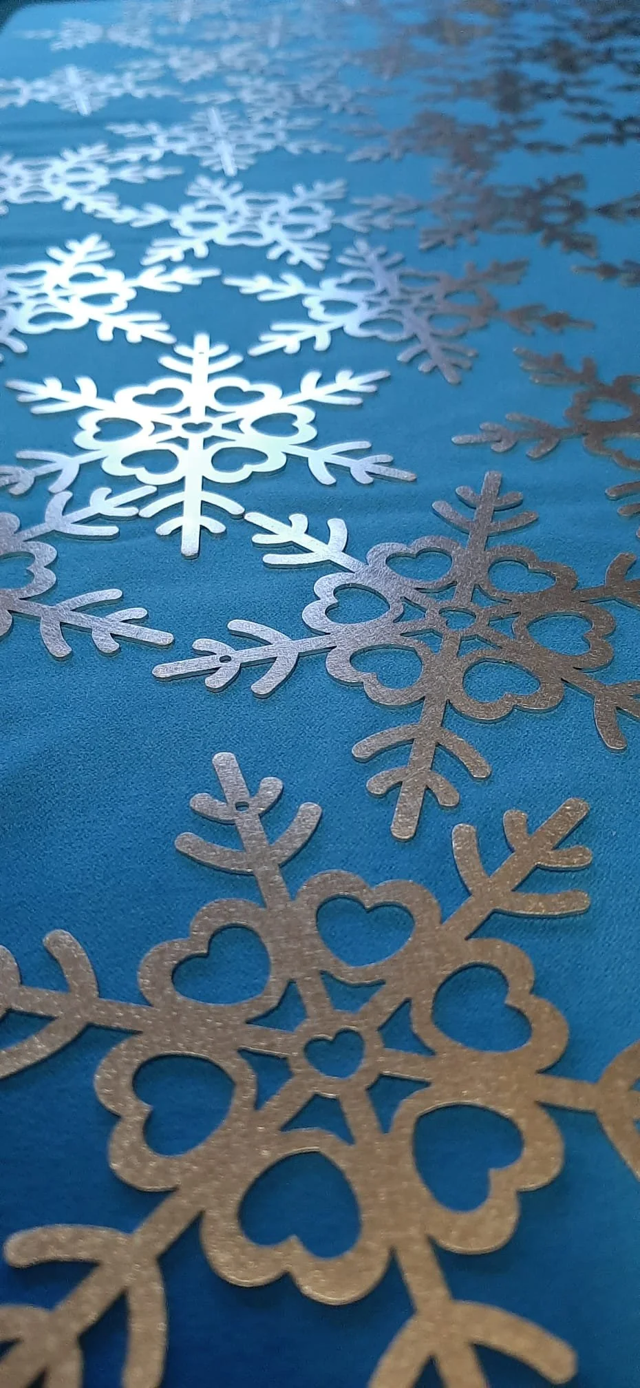 Close-up of interconnected silver snowflakes on a blue surface.