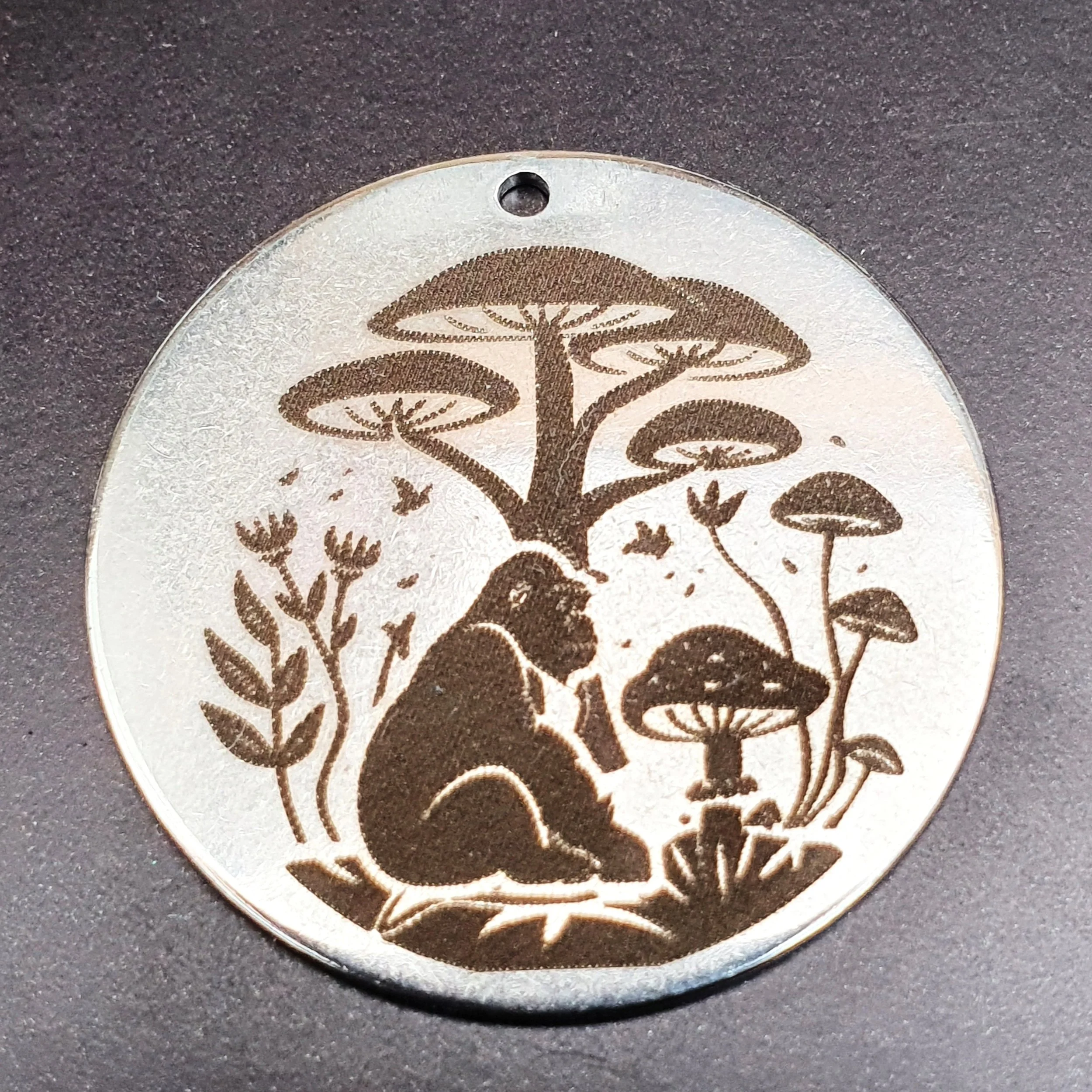 A round coin with artwork of a gorilla sitting among large mushrooms and tall plants in a forest setting.