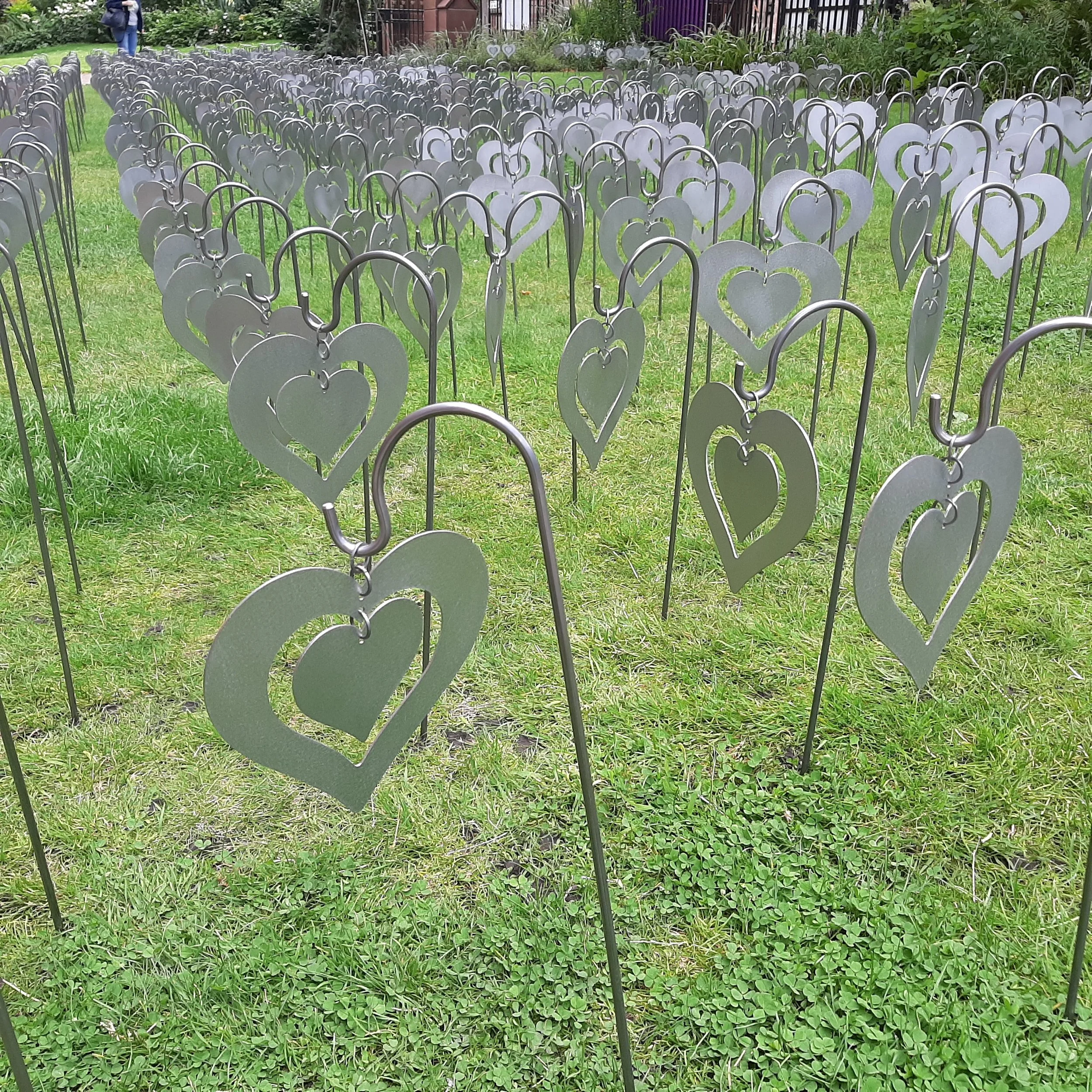 Metal garden stakes with heart-shaped cutouts in a grassy area.
