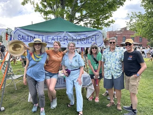 Group of six people standing outdoors in front of a tent with a banner that reads 'Salado Theater Project'. They are smiling and dressed casually.