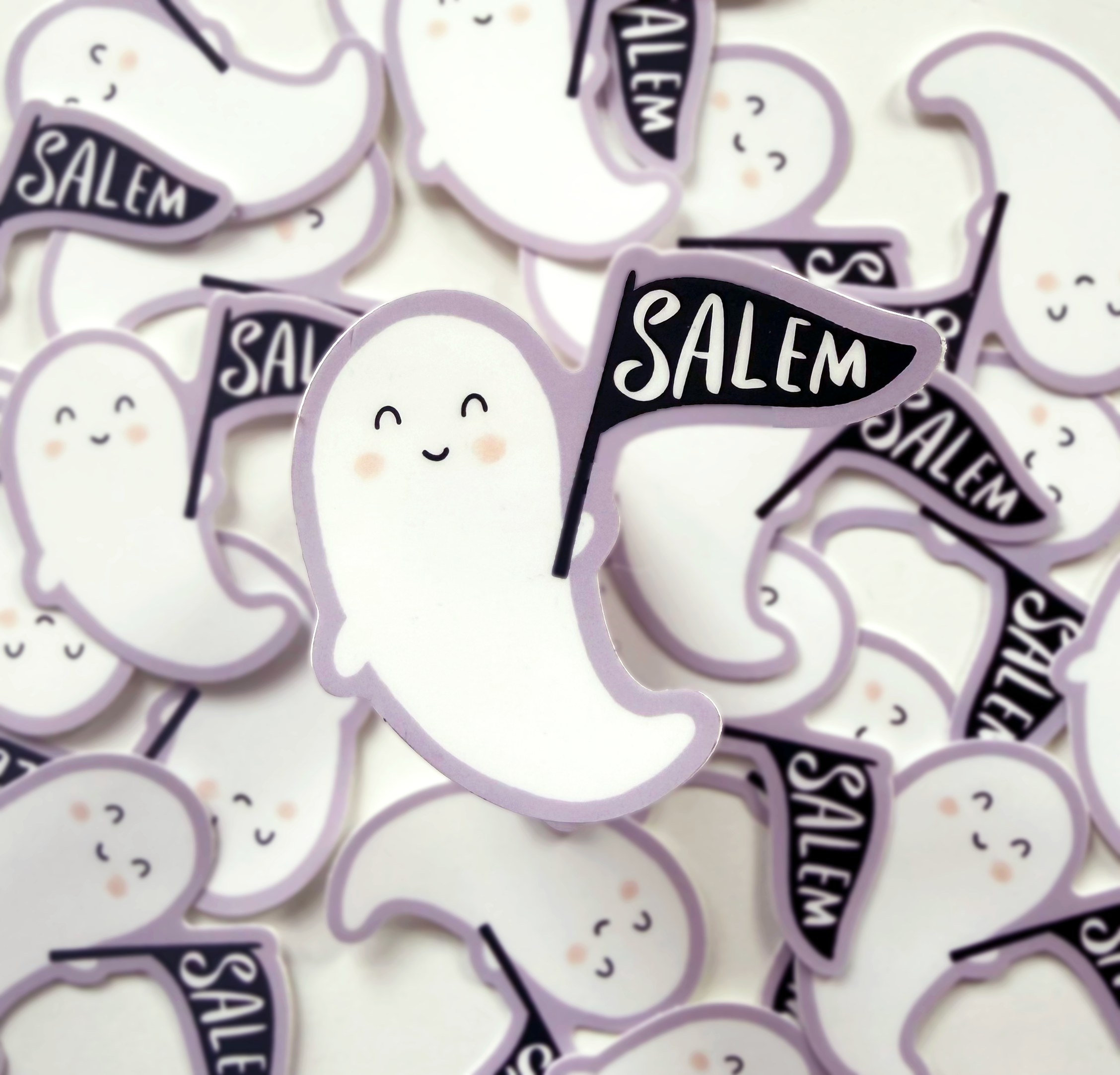 Blushing ghost sticker holding a black flag that says Salem