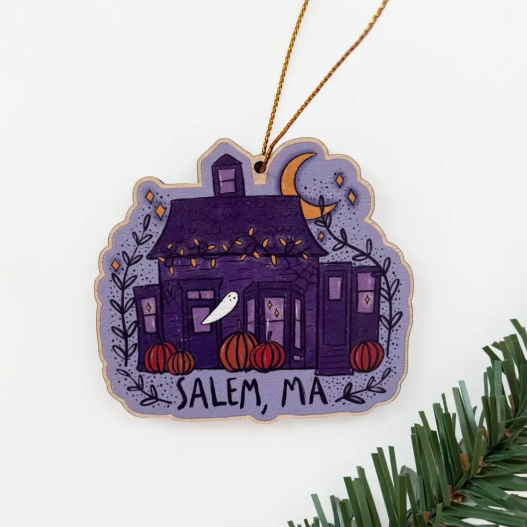 ocean ave house with purple walls and roof, small pumpkins out front with a ghost by the window
