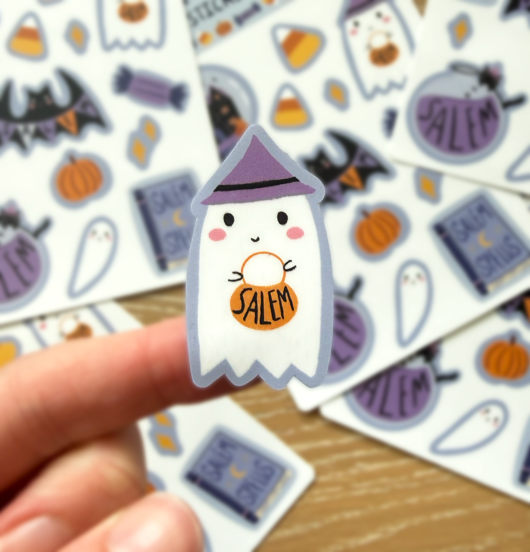Closeup of the ghost with a purple witch hat holding a pumpkin shaped basket that says Salem on it in black text.