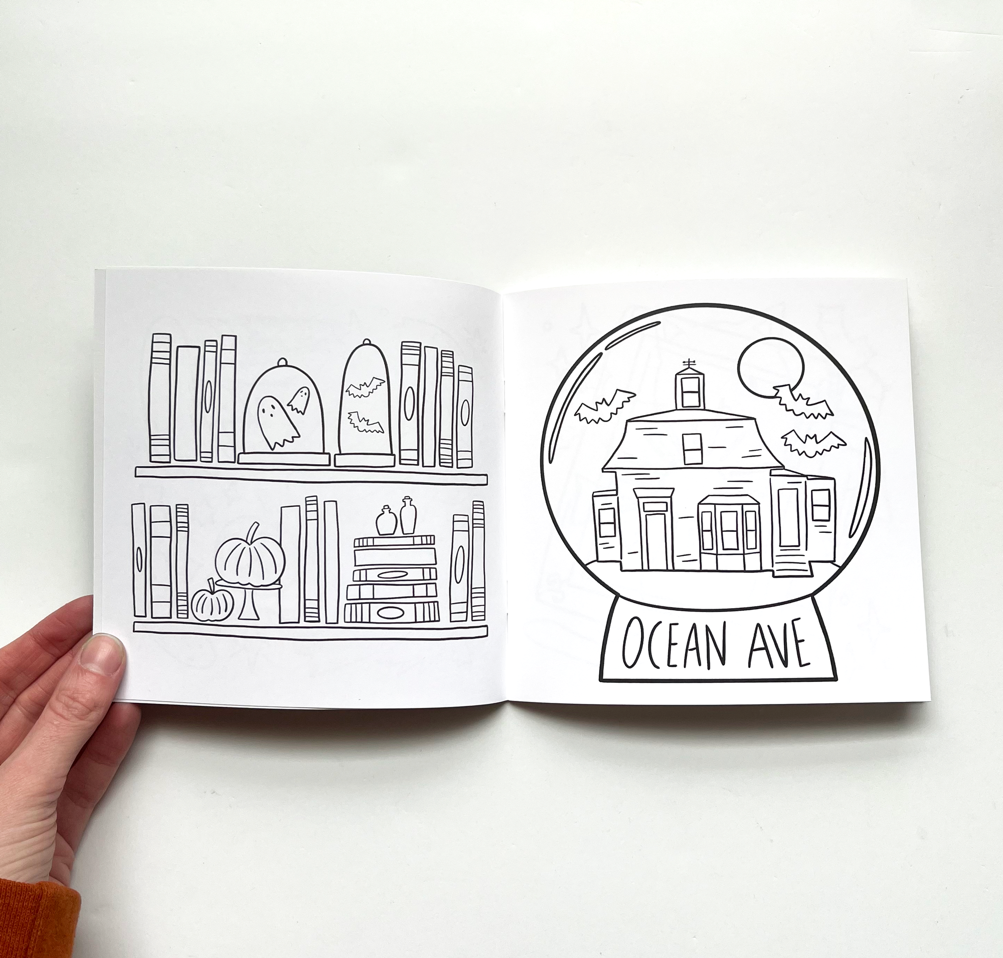 open coloring book showing ropes mansion page and shelf of halloween things
