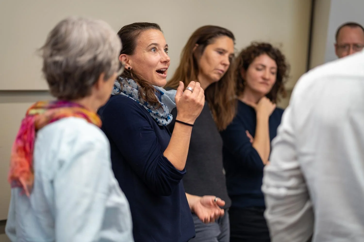 A group of women engaged in a discussion during a meeting, with one woman speaking animatedly.
