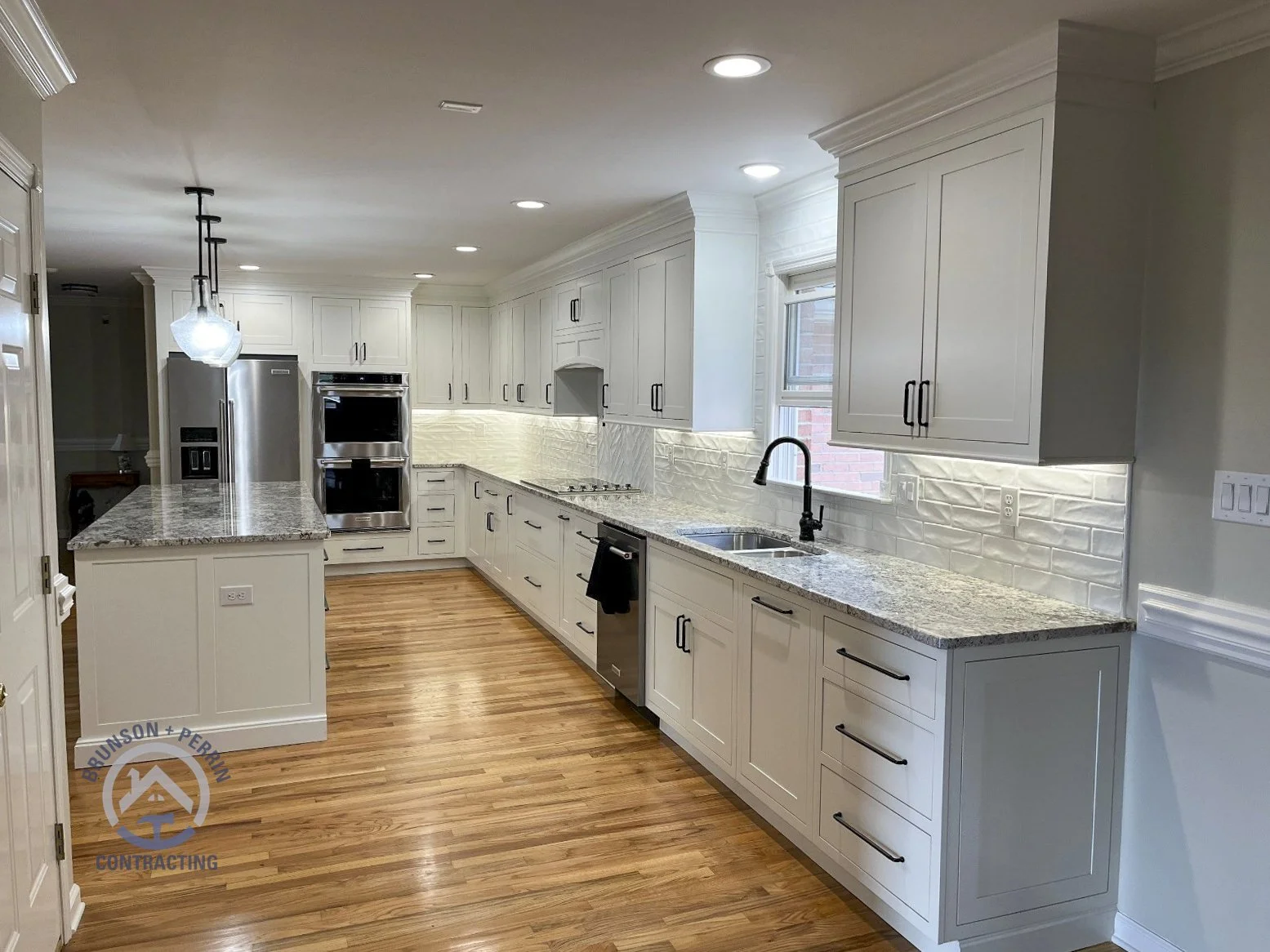White shaker cabinets with matte black hardware, granite countertops, a double-basin sink, matte black faucet, and a white textured tile backsplash in a custom Johnson City, TN kitchen remodel. Partnership with Katy Lynn Cabinetry & Design.