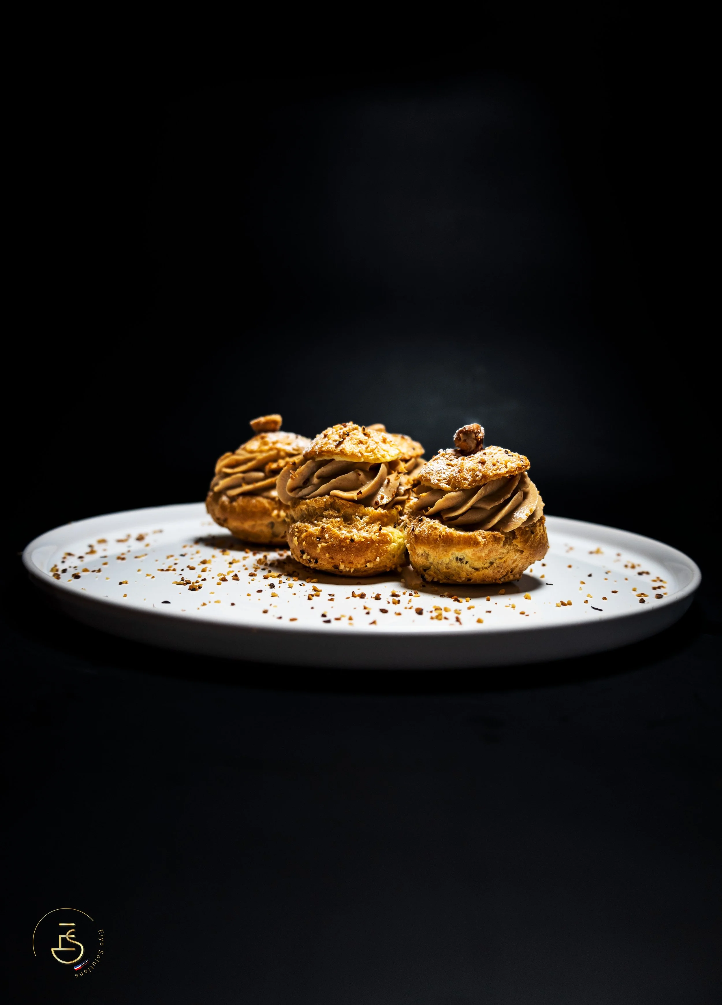 Trio de choux garnis de crème praliné chocolat sur assiette grise avec éclats de noisettes torréfiées, dessert gastronomique restaurant