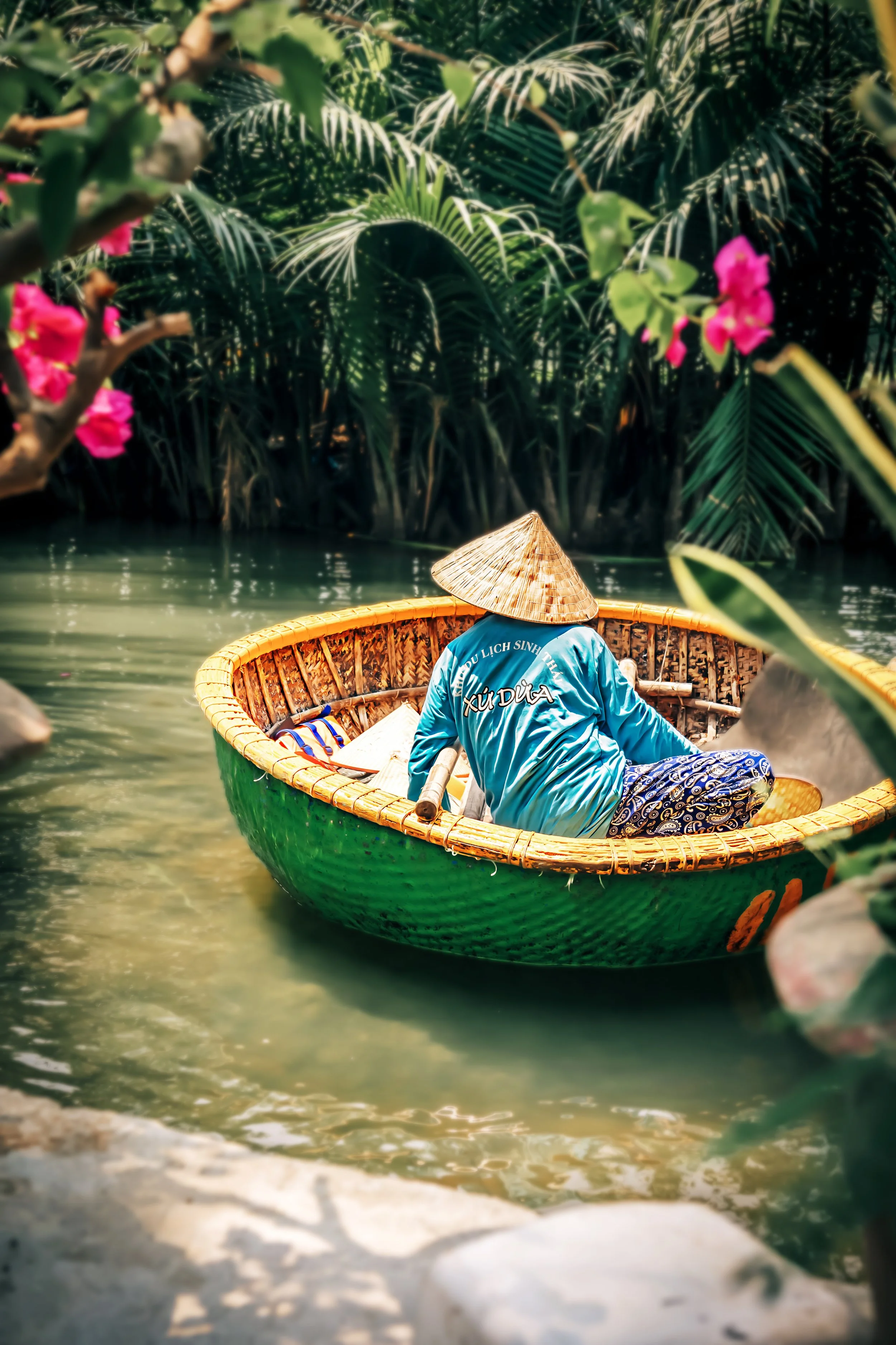 Pêcheur en barque ronde traditionnelle en bambou sur une rivière tropicale au Vietnam, tourisme authentique