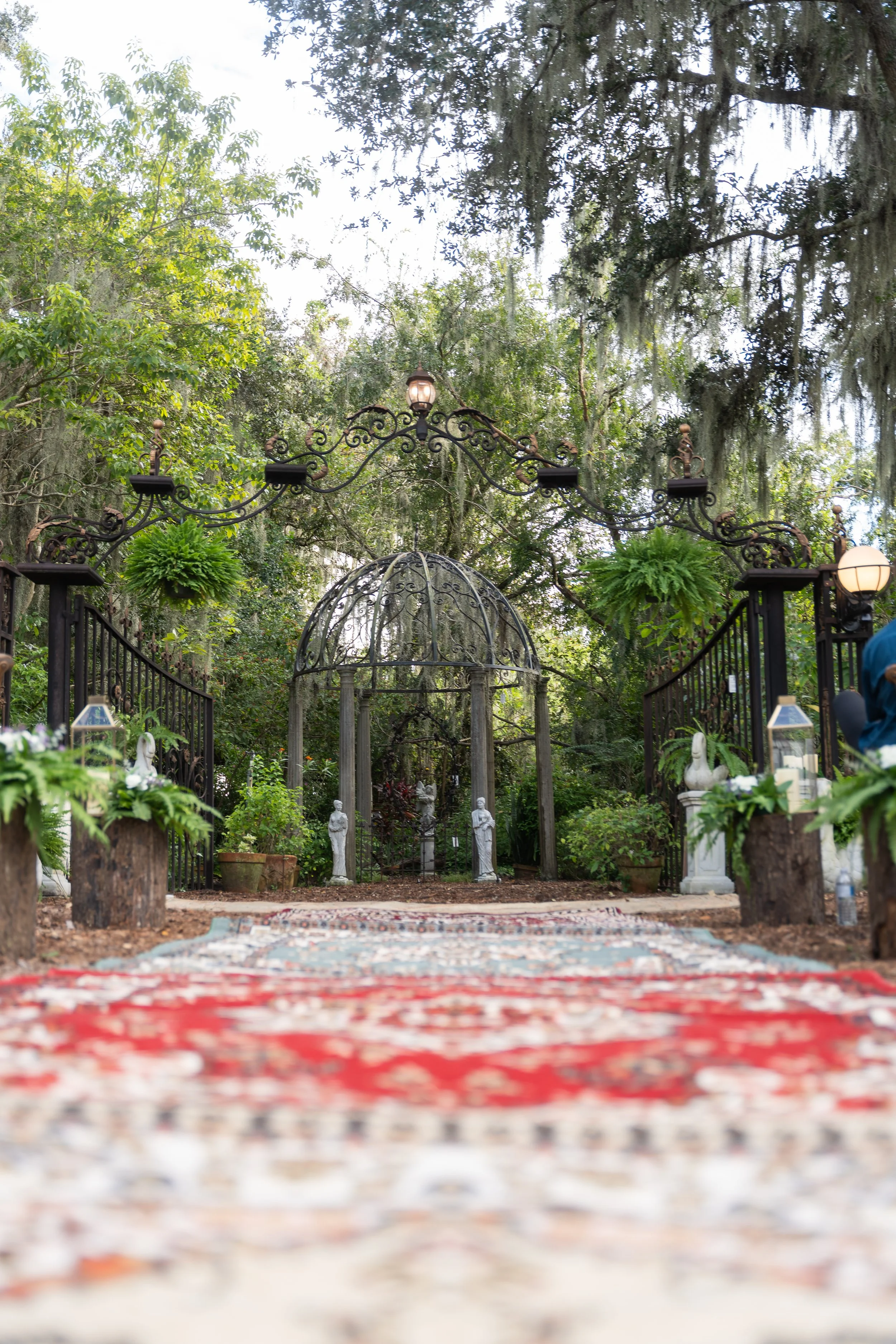Antique rugs, preserved moss, and lanterns creating an enchanted wedding aisle