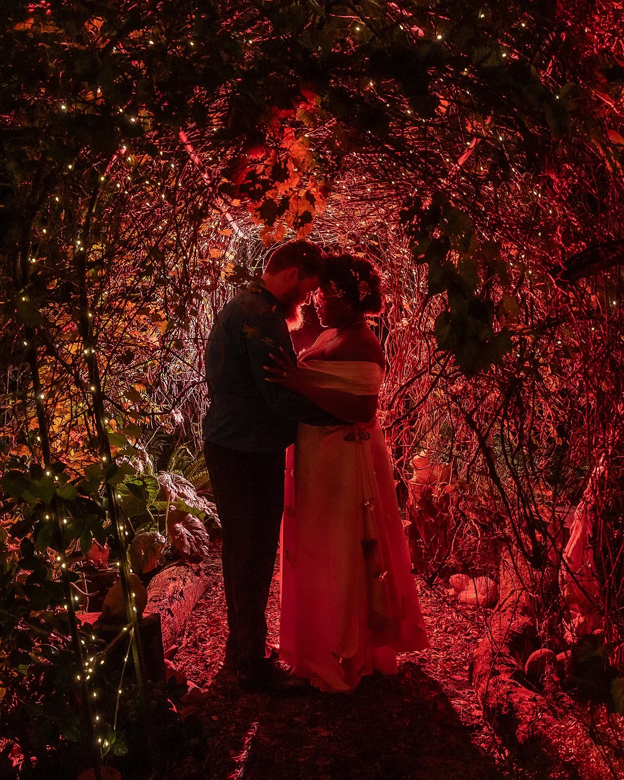 Romantic couple portrait surrounded by greenery and soft garden light
