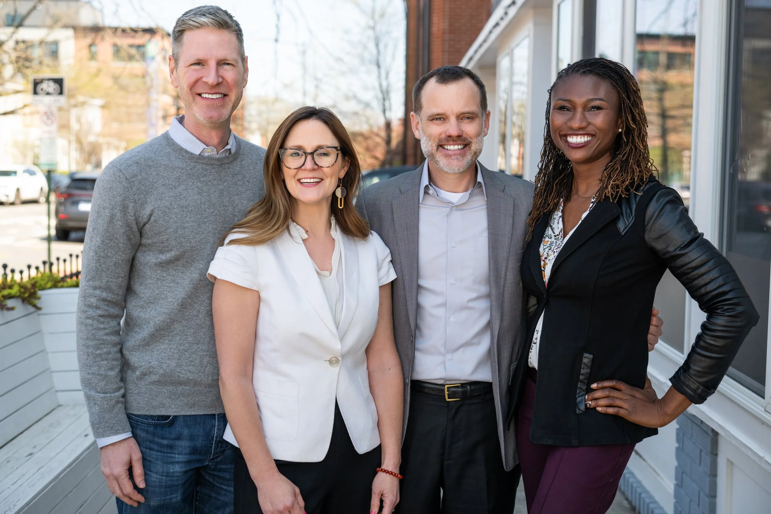Group of five smiling professionals standing outdoors.