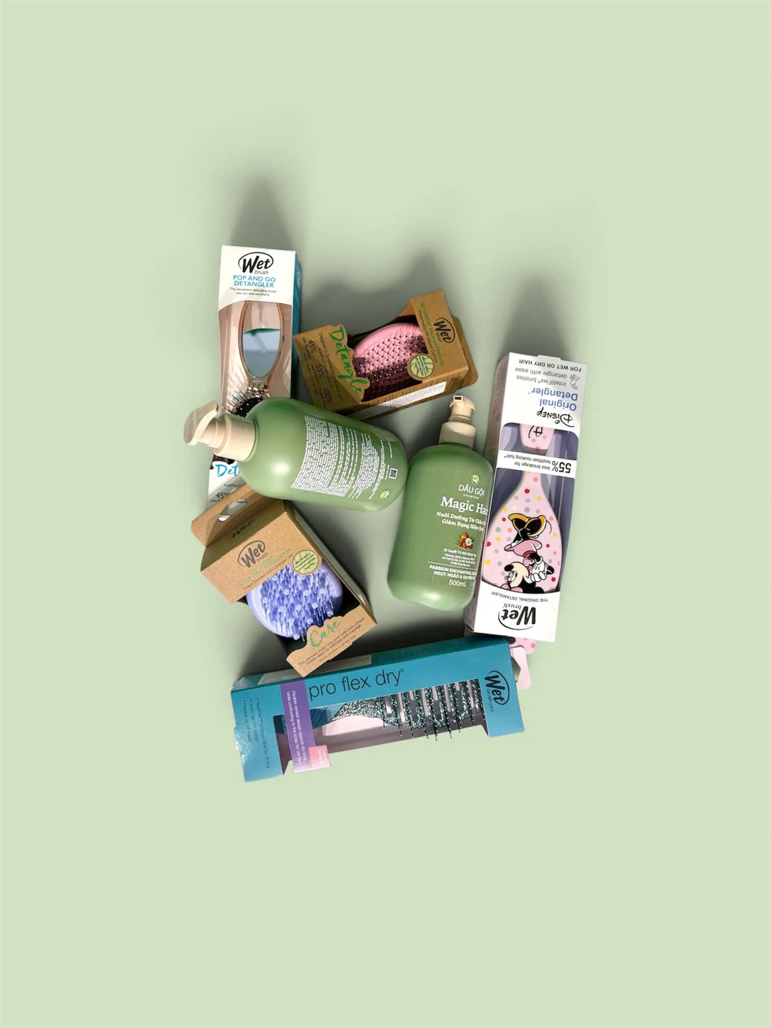 Collection of hair care and grooming products including brushes, shampoo, and hair treatment items on a green surface.