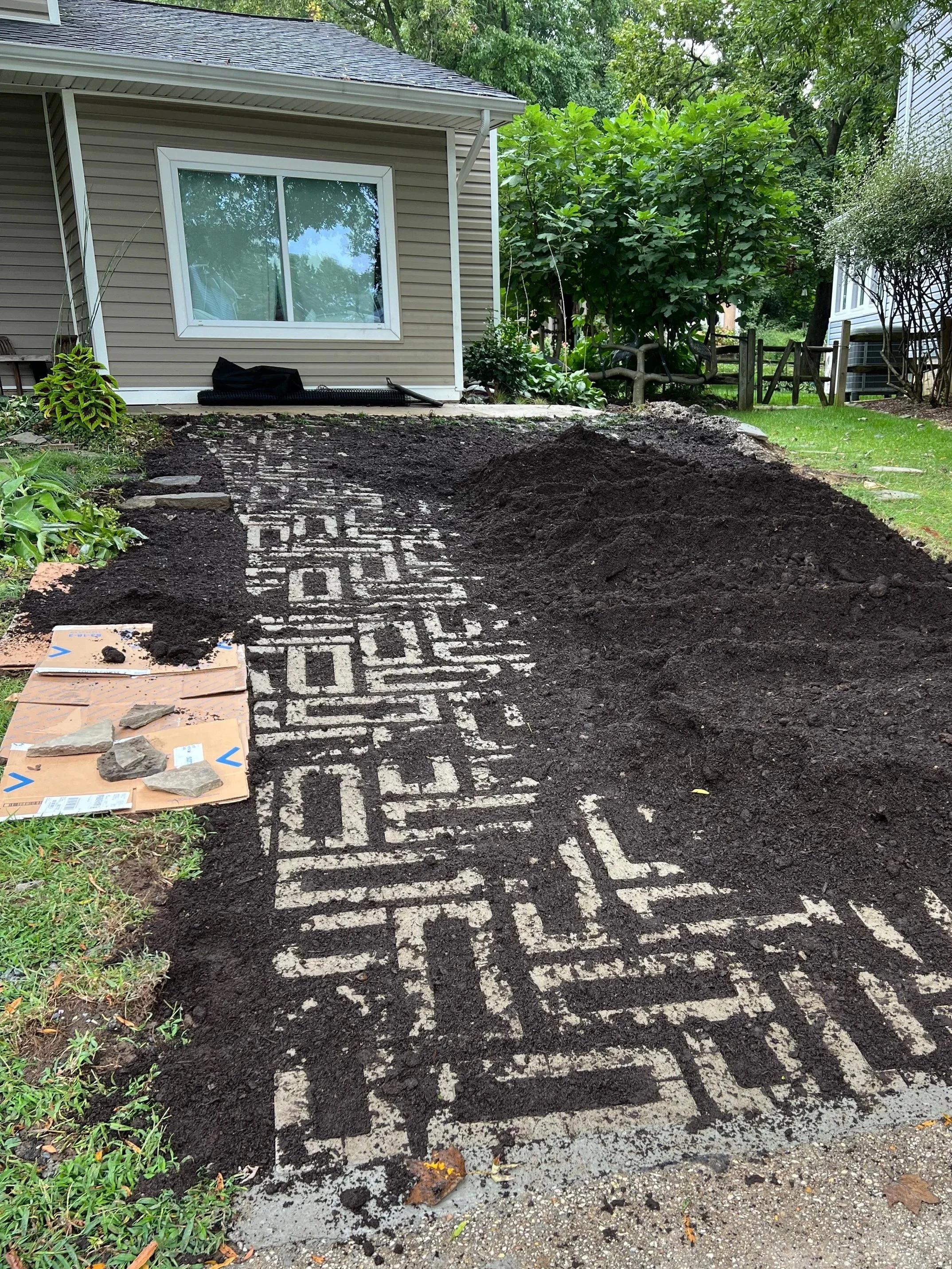 Topsoil was brought in.  Knowing I was going to plant Pennsylvania Sedge to the right, I layed cardboard on the grass to smother it and topped it off with the topsoil.  No dig turf removal!  