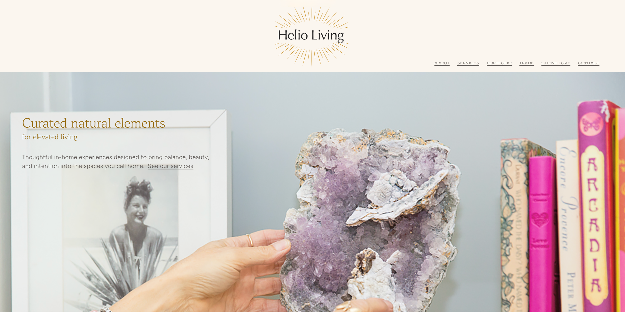 Hand holding a large purple and white mineral or crystal with a background of a framed black-and-white photo of a woman and a bookshelf with colorful books.