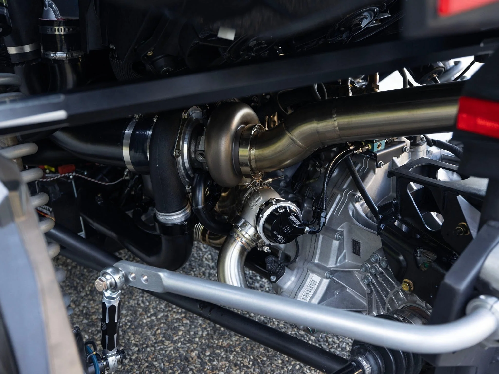 Close-up view of a high-performance car engine with visible turbocharger, exhaust piping, and mechanical components.