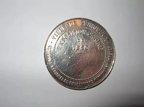 Médaille ou pièce de monnaie en métal avec inscription en français.