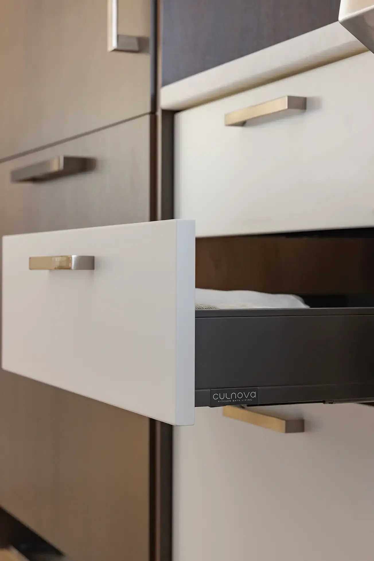 Open drawer in a modern kitchen cabinet with of brand Culnova visible on black section.