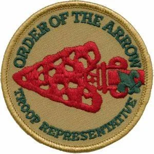 Patch with a beige background, green border, and red design of a heart-shaped fish hook. Contains text "ORDER OF THE ARROW NATIONAL REPRESENTATIVE" around the edge.