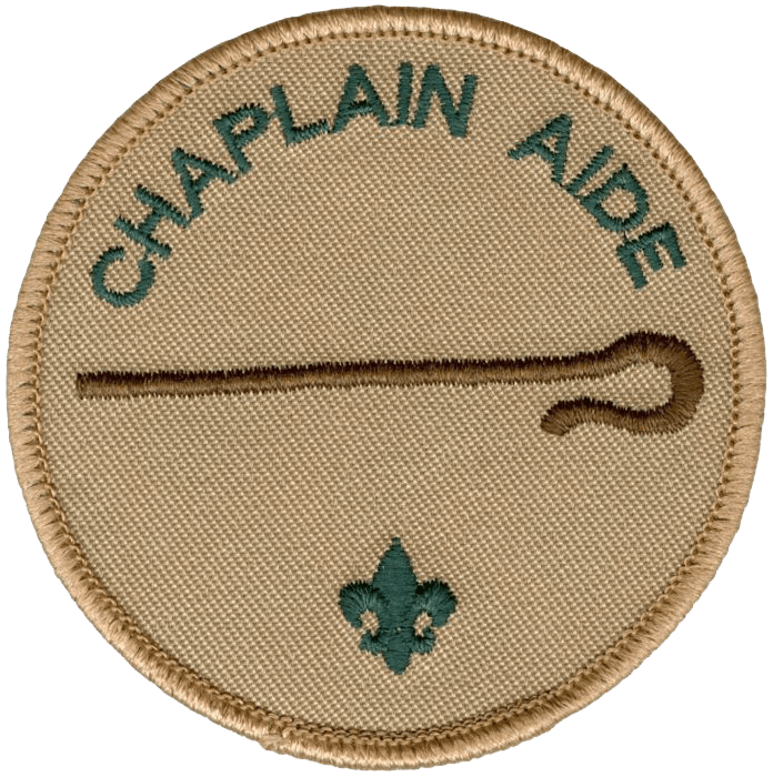 Boy Scout merit badge with a beige background, green text reading 'Chaplain Aide', a brown line, and a small Fleur-de-lis symbol at the bottom.