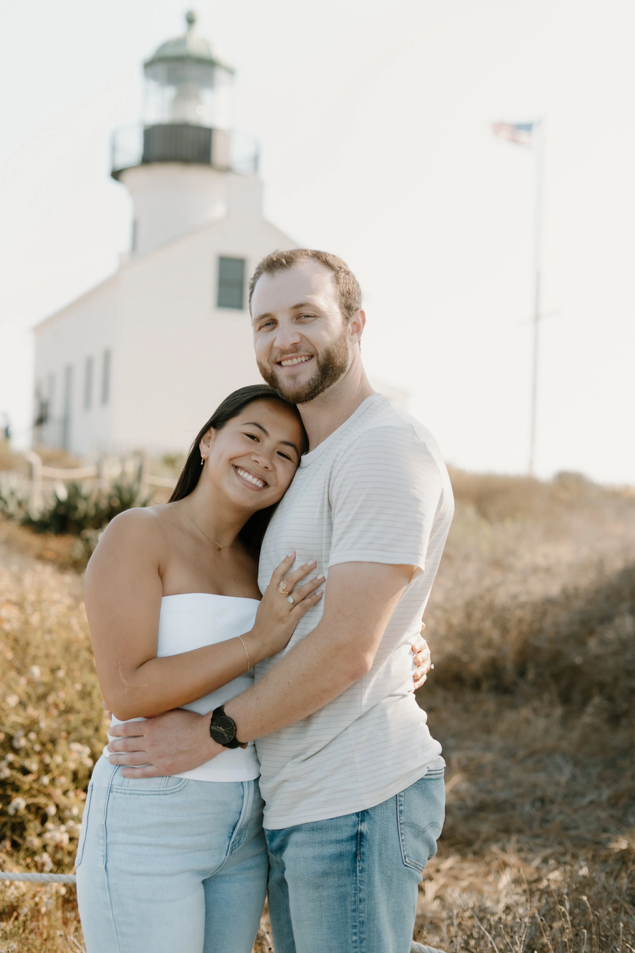 engaged-couple-cuddling-light-house.jpg