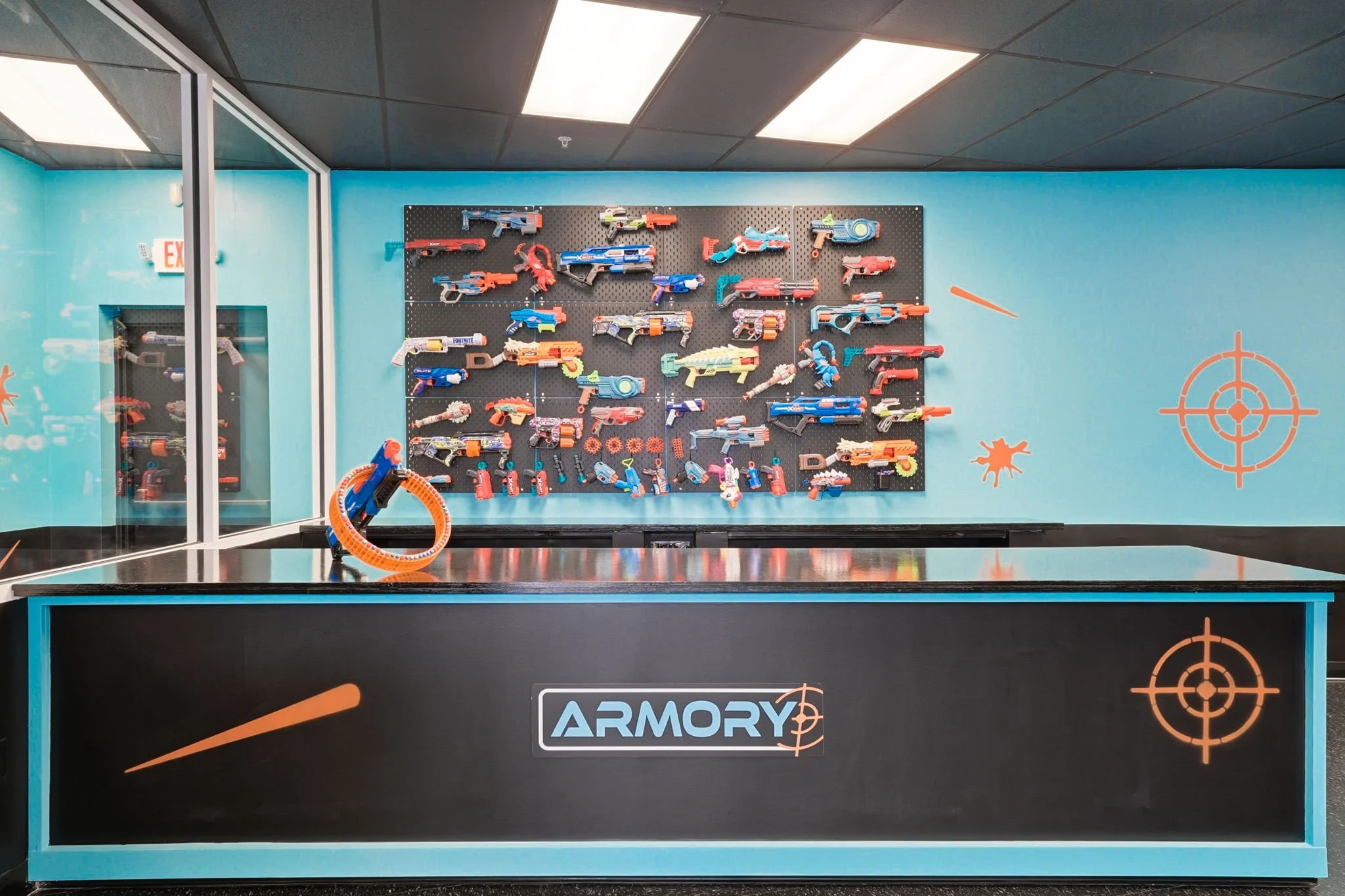Indoor Nerf arena armory wall with Nerf blasters display, laser tag and airsoft-style gameplay equipment, birthday party venue in Marietta Georgia