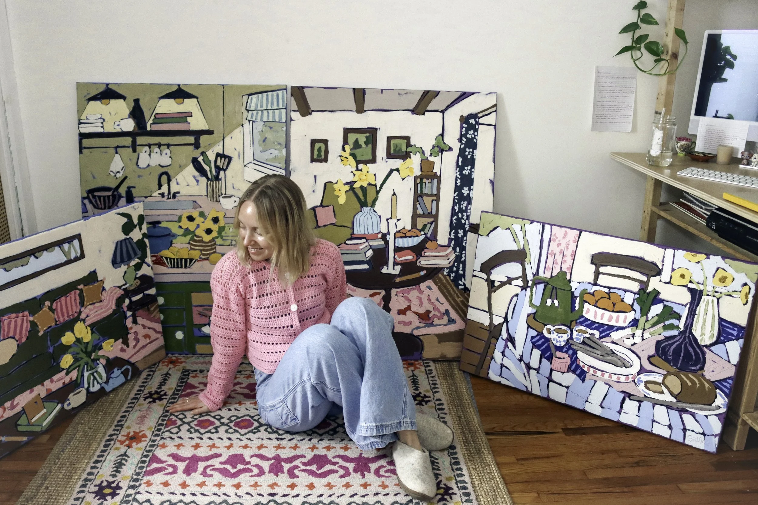 artist sitting among her oil paintings in her art studio