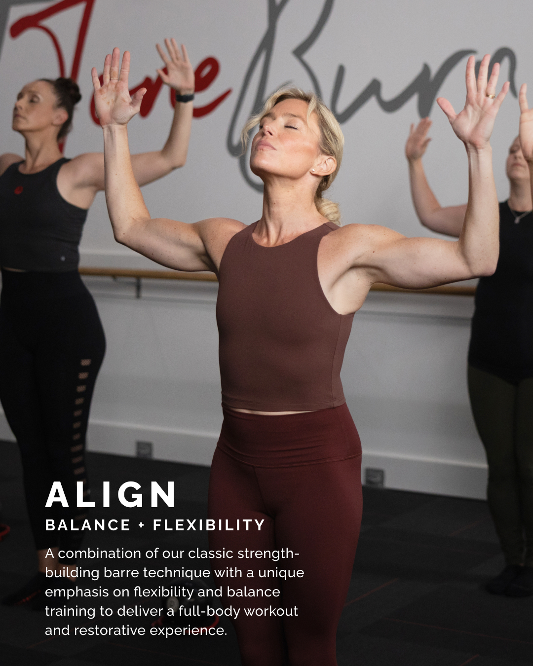 Women participating in a fitness class, demonstrating balance and flexibility with their eyes closed and arms raised. The setting appears to be a gym or studio with the word "Love" partially visible on the wall.