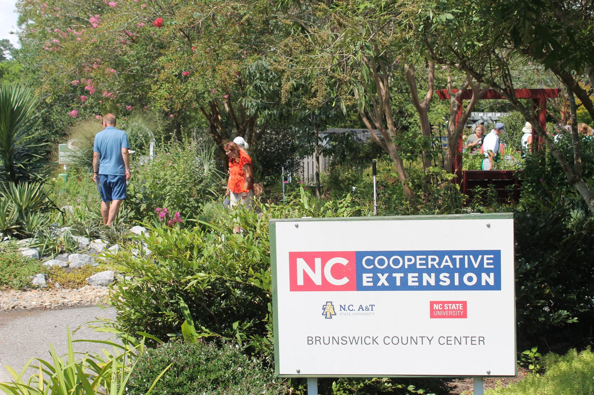 Pollinator Census participants explore the Botanical Garden behind the Brunswick County Cooperative Extension sign.