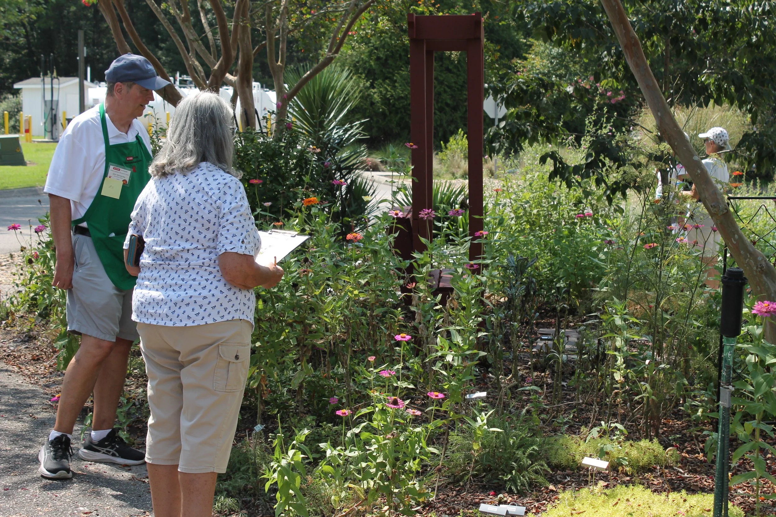 Master Gardener volunteer assists a Pollinator Census participant as they observe and record pollinators in the Botanical Garden.
