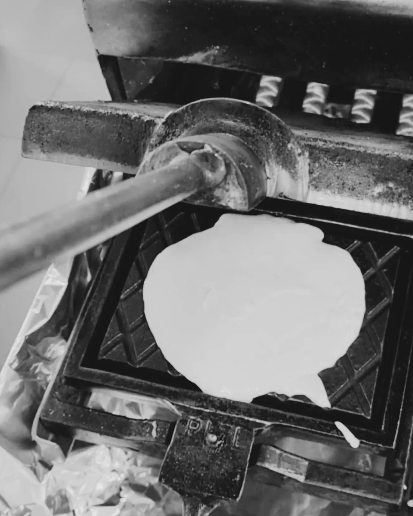 Une galette de pâte à pizza sur une plaque en métal, chauffée par une poêle ou un four à gaz.