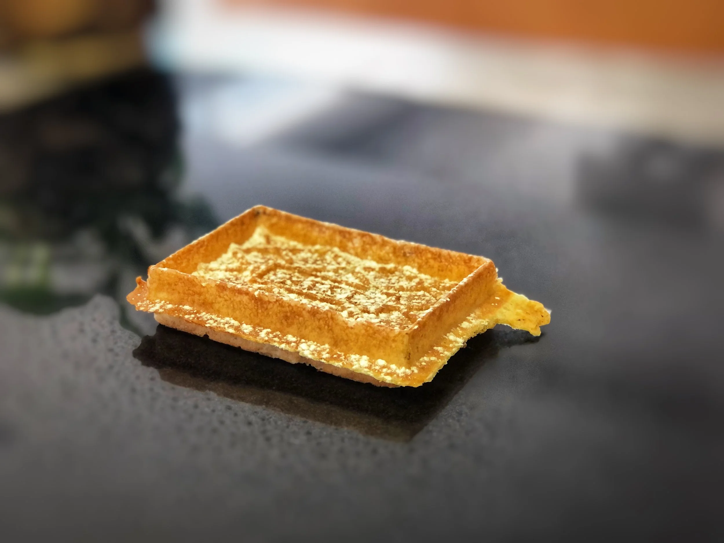 Une langue de chat, biscuit fin, posé sur une surface sombre